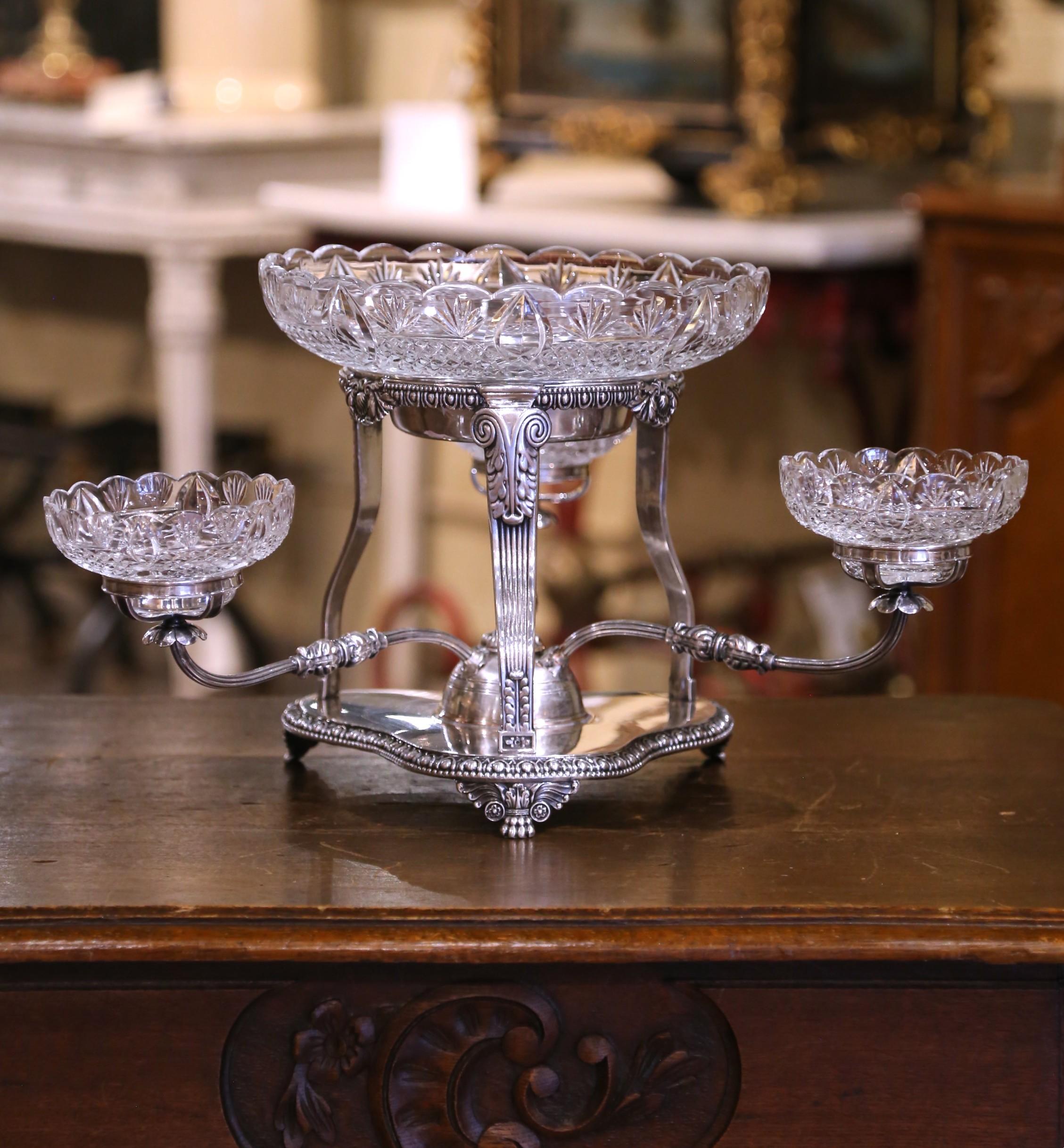 Bringen Sie Grandeur und Raffinesse auf Ihren Tisch mit dieser eindrucksvollen englischen Epergne aus dem 19. Jahrhundert, die im Stil von George III. gefertigt wurde. Der versilberte Kupferrahmen ruht auf einem eleganten, geformten Sockel mit