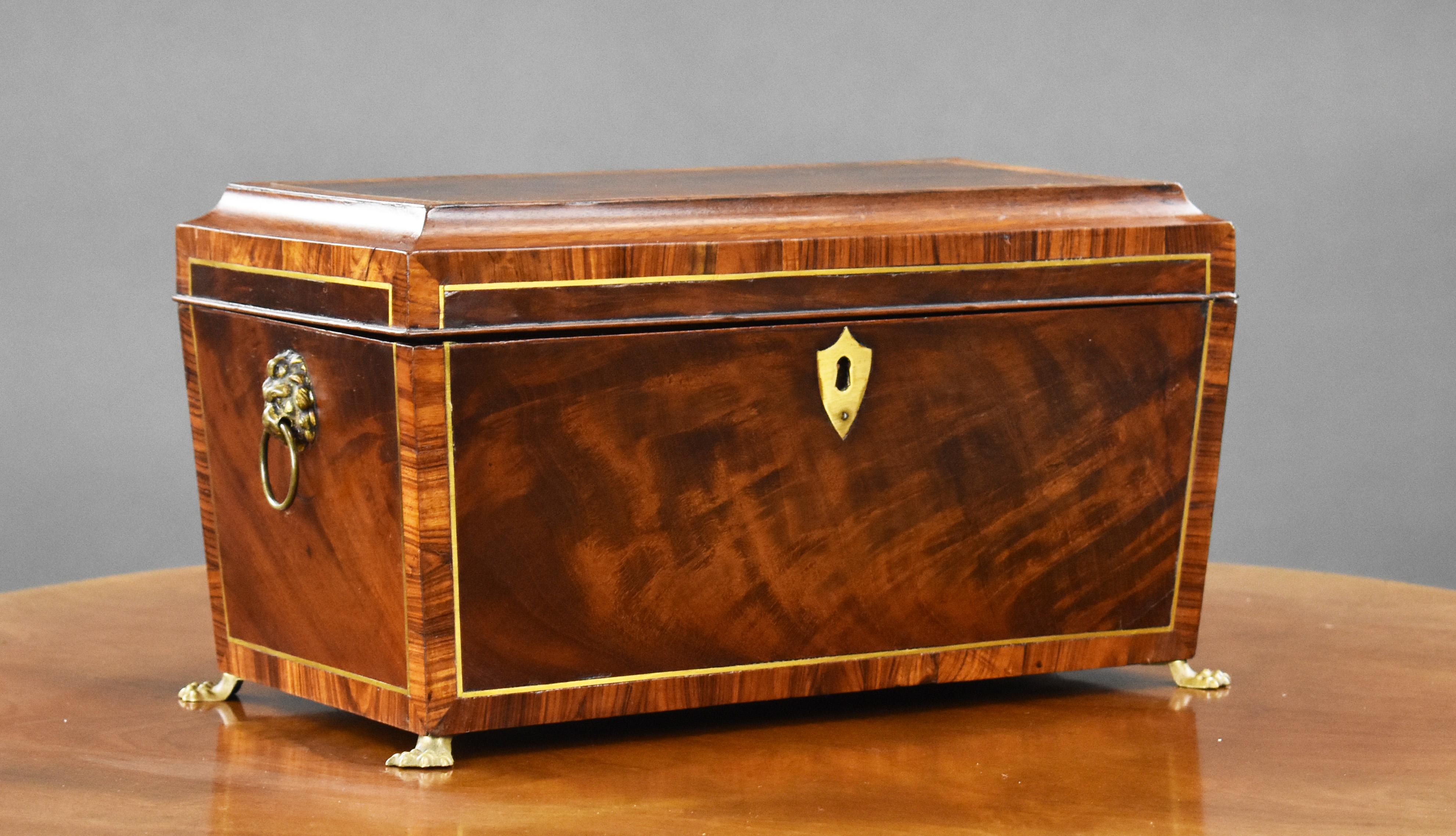 A good quality George III flame mahogany tea caddy. Of classic sarcophagus shape, decorated with cut brass stringing and rosewood cross banding, the top open to reveal two twin lift out caddies with hinged lids for green and black teas as well as a