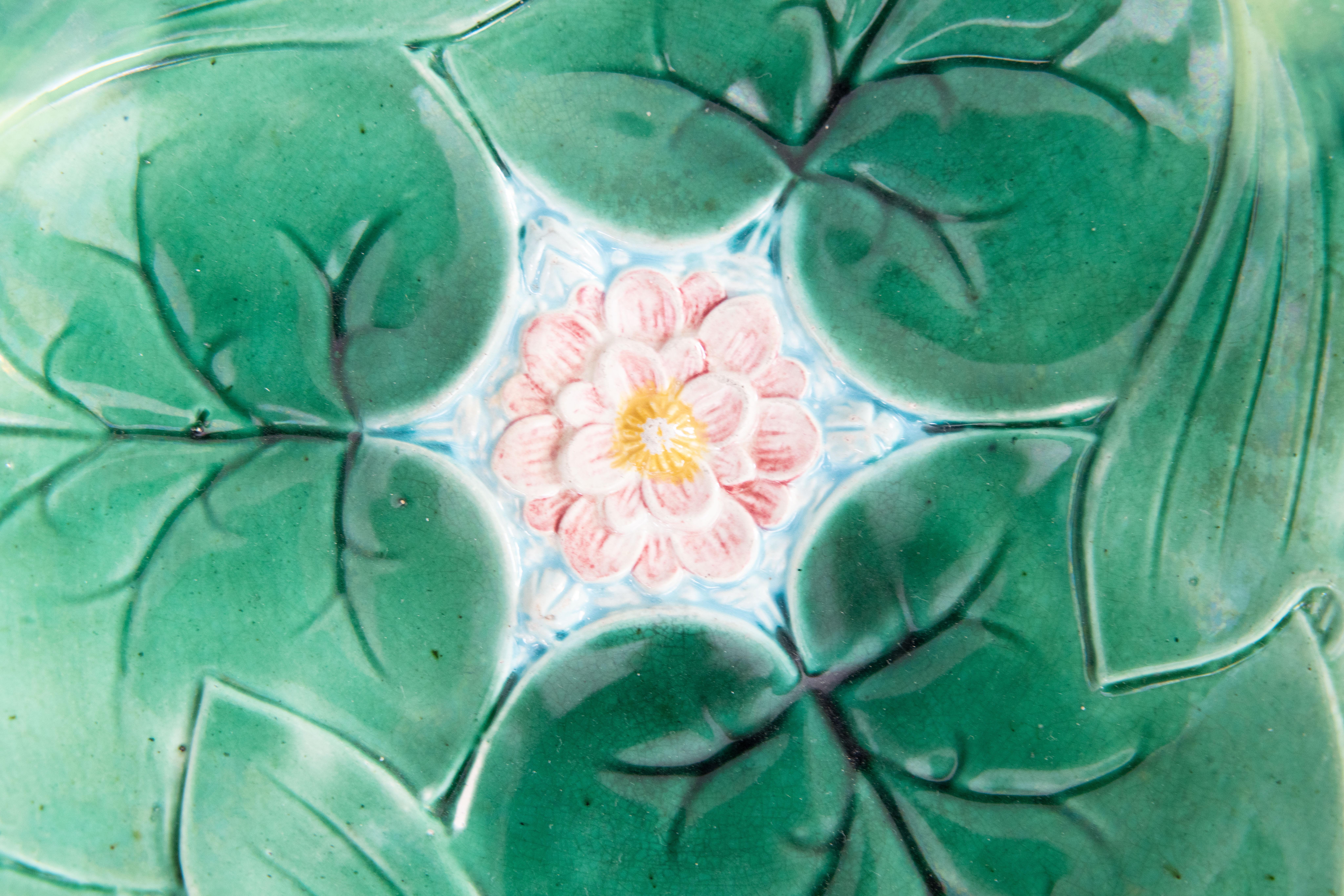 Un delizioso piatto antico inglese George Jones in maiolica smaltata verde con fiori di loto, circa 1870. Questo bellissimo piatto è dipinto a mano con grande attenzione ai dettagli e con colori squisiti dal rinomato produttore di maioliche George