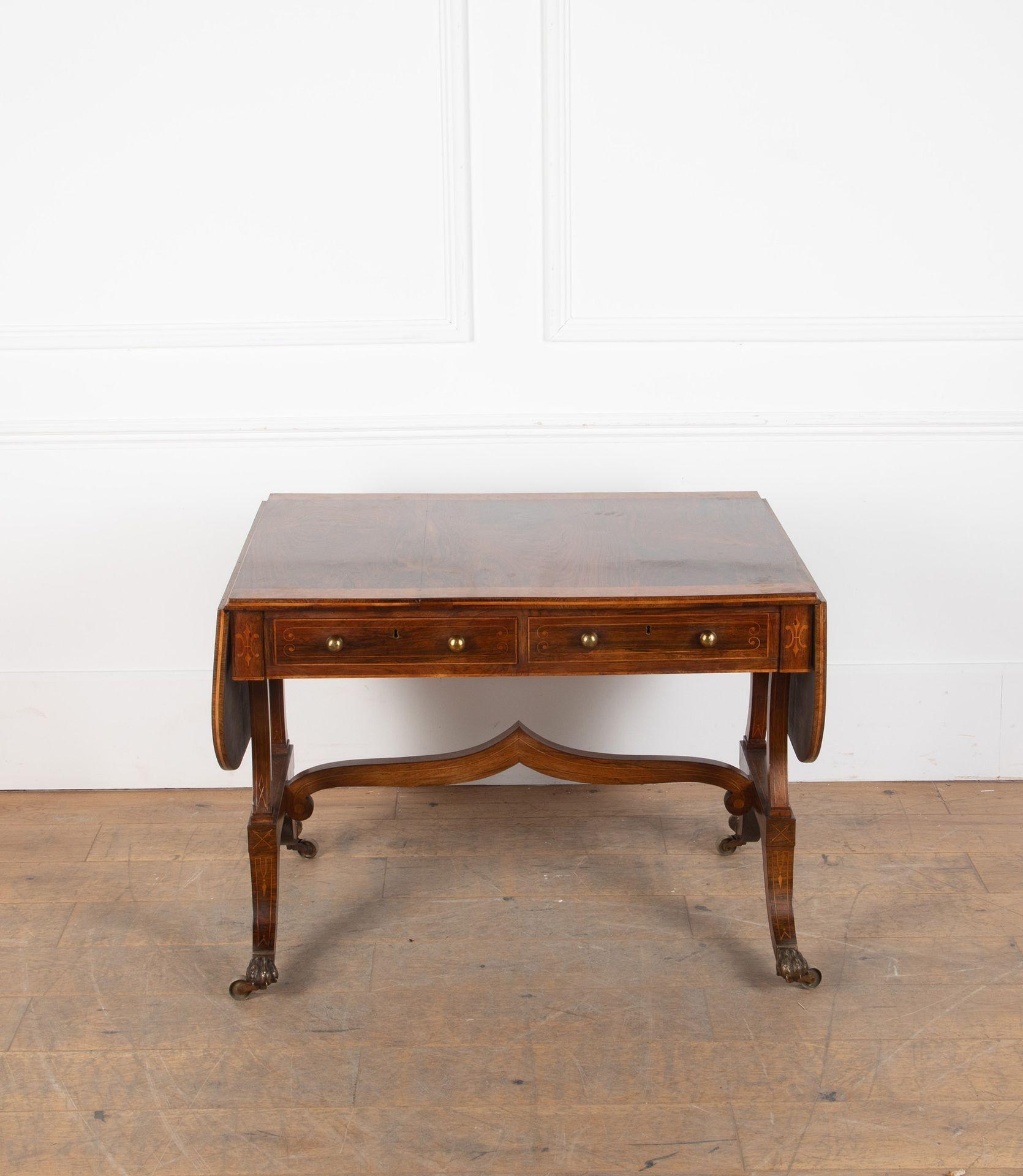 Regency amboyna banded rosewood sofa table.
With two frieze drawers and drop leaves on both ends, splay legs on brass paw feet and castors.
England, first quarter of the 19th Century.