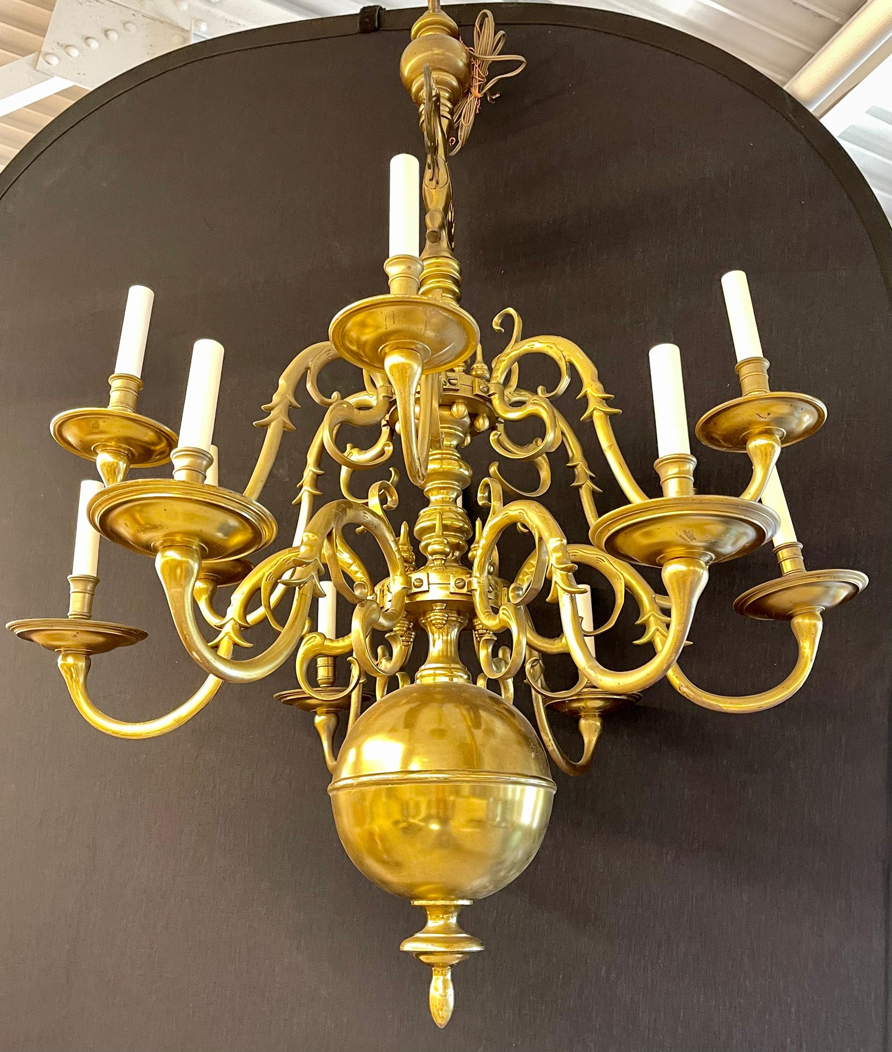 English Georgian style bronze chandelier having a pair of rare winged eagles on top of the many scrolled and lighted arms attached to a turned column ending with large brass orb and finial. Late 19th century/ early 20th century.