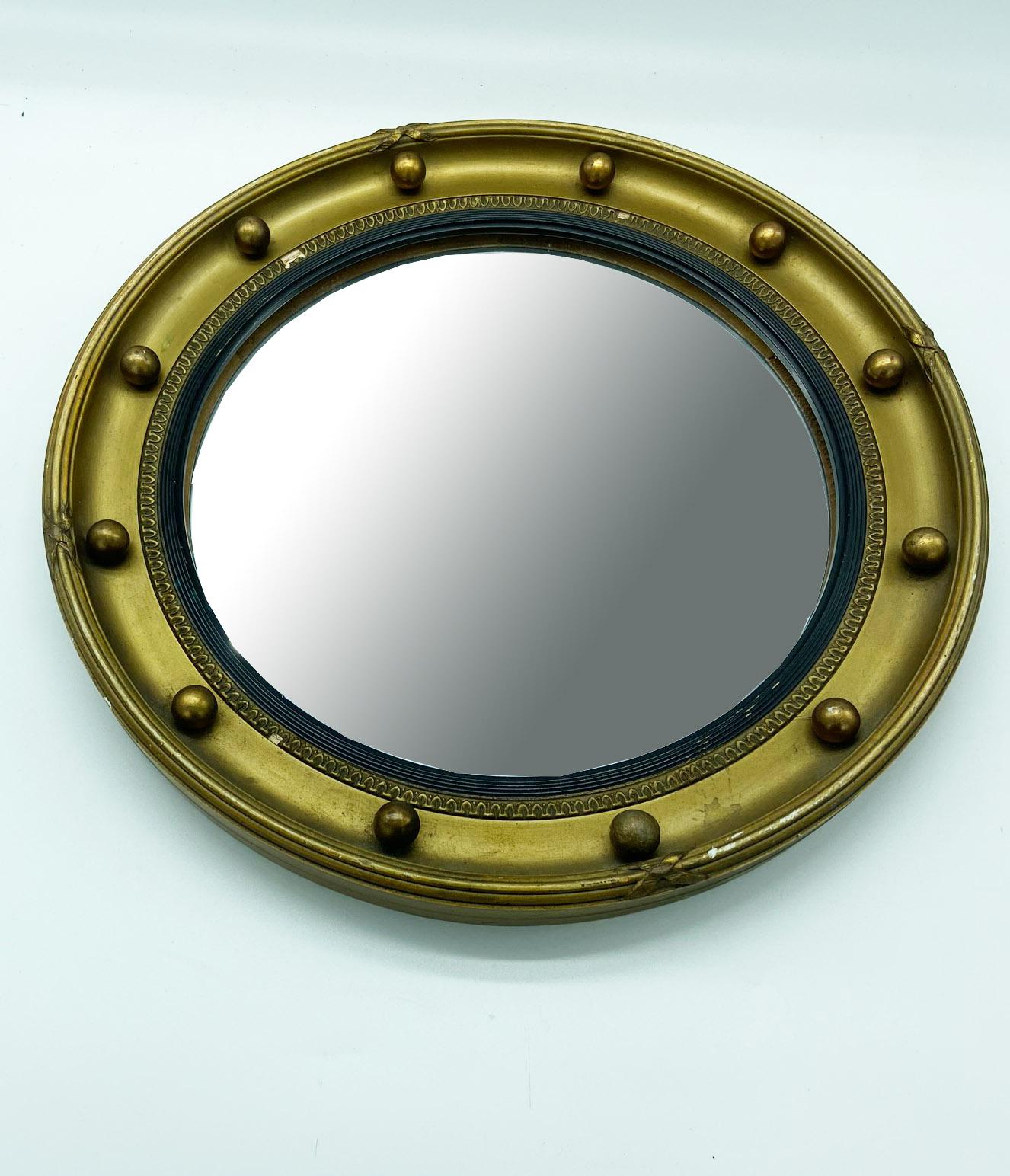 An English painted wood bullseye mirror from the late 19th century. The painted wood outer frame, whose gold color presents a perfect contrast to the dark hue of the inner frame, is delicately adorned with petite balls.