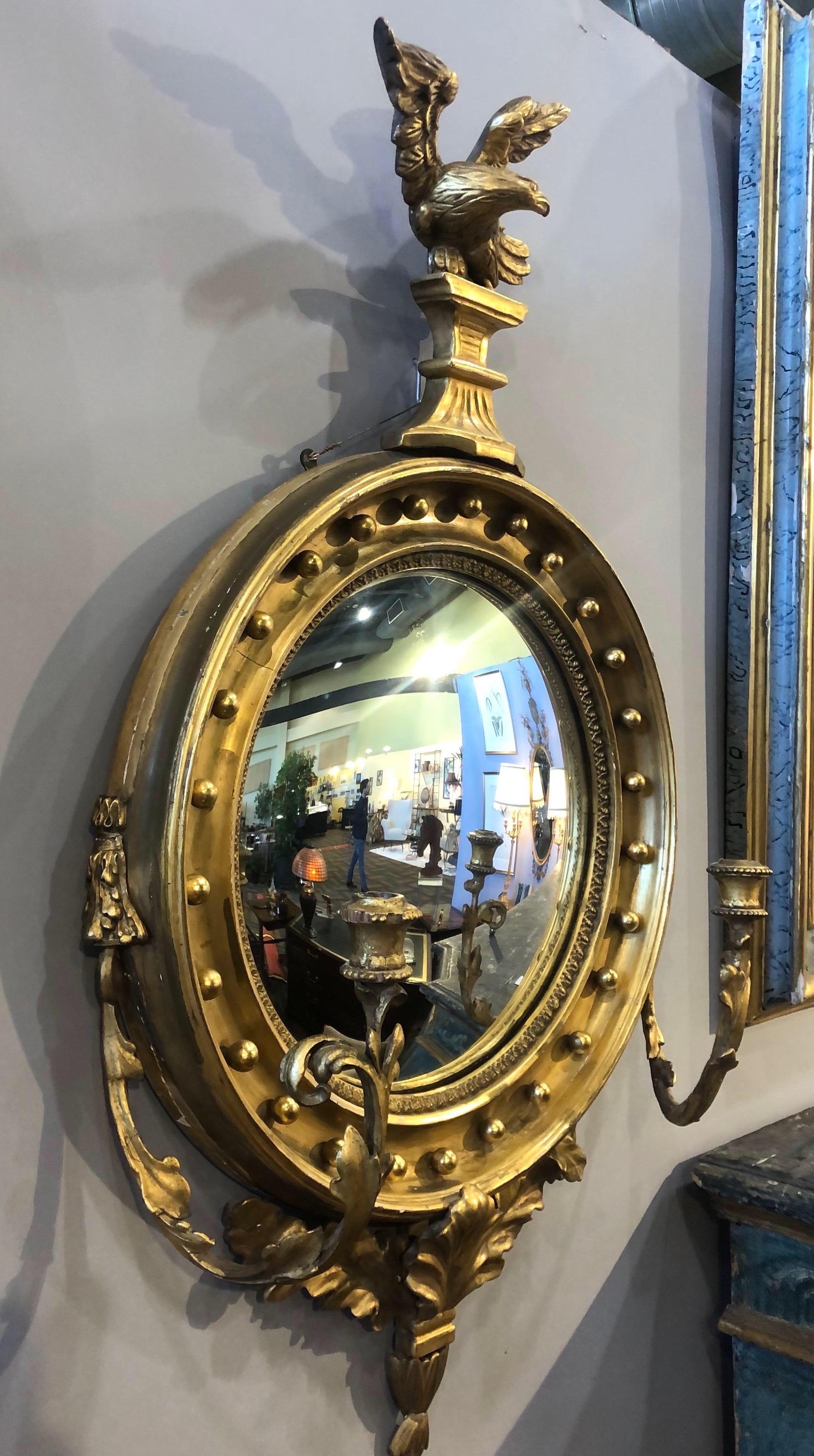 Beautiful English convex mirror with girandole arms. Mirror i topped with a carved eagle and resting on leaf and floral carvings. 

Label on back indicating it was sold in Dover, England.