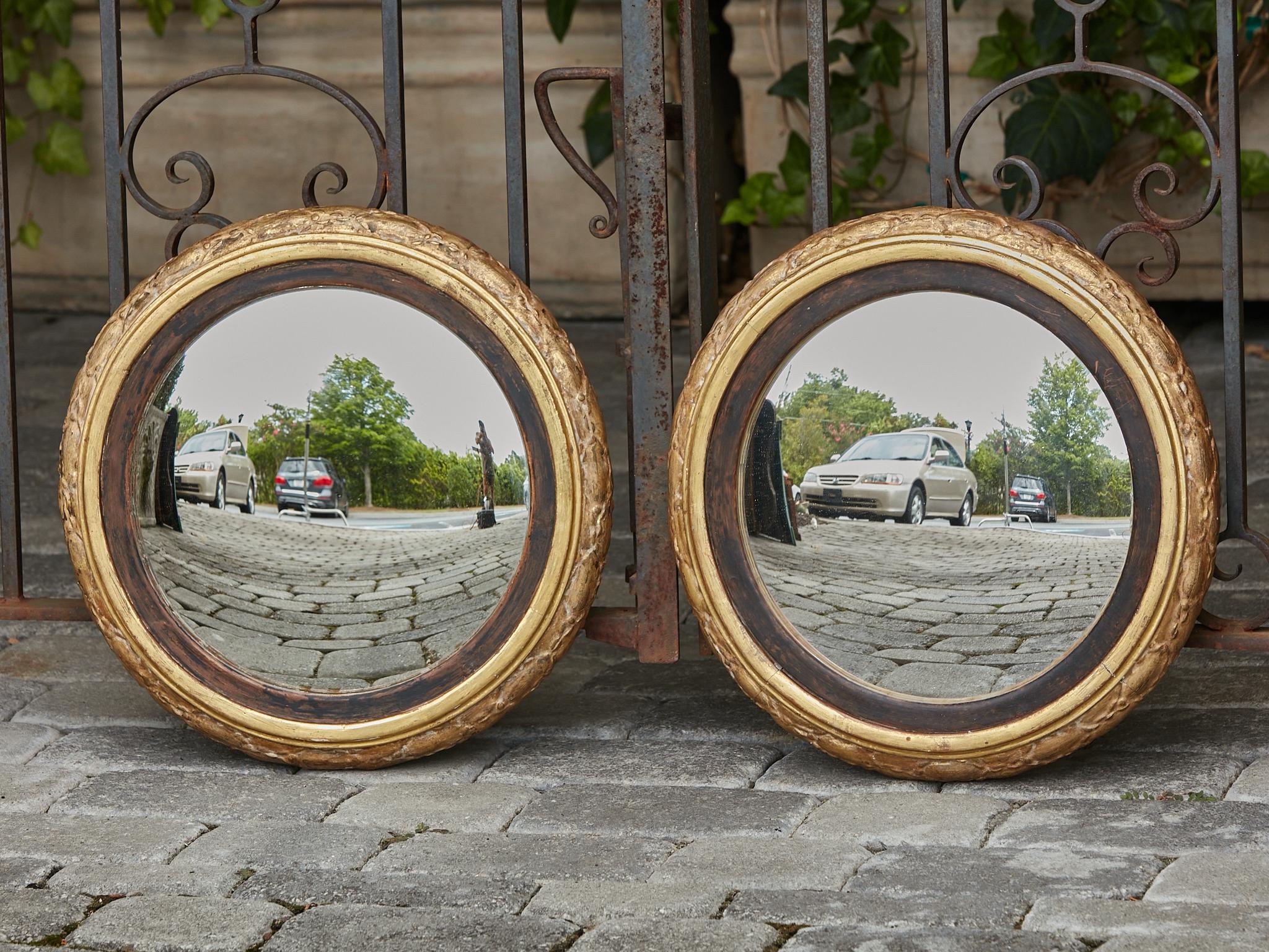A pair of English giltwood convex mirrors from the 19th century with carved foliage. This stunning pair of 19th-century English giltwood convex mirrors exudes timeless elegance and artisanal craftsmanship. Each mirror features a convex mirror plate,