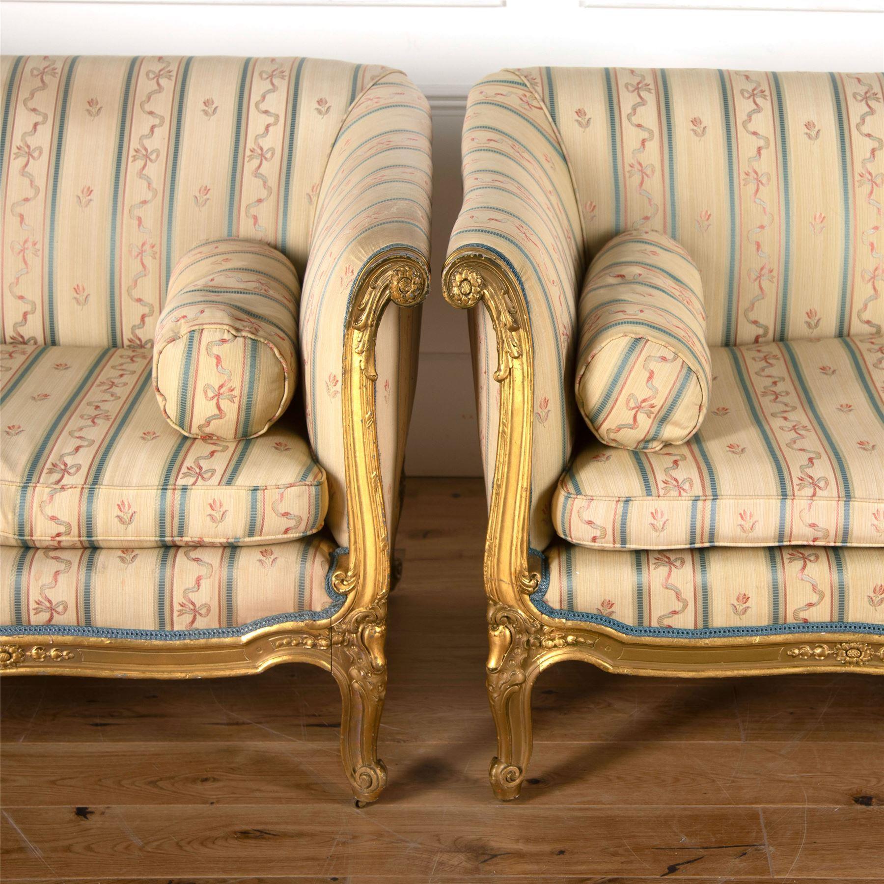 A pair of 19th century English sofas in the French manner with carved gilt wood show frames.