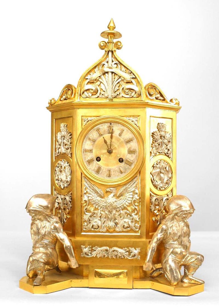 English Gothic Revival style (19th Cent) gilt mantle clock with silver plate decoration and supported by 2 gnome figures with a pediment having a finial top. *Not working
