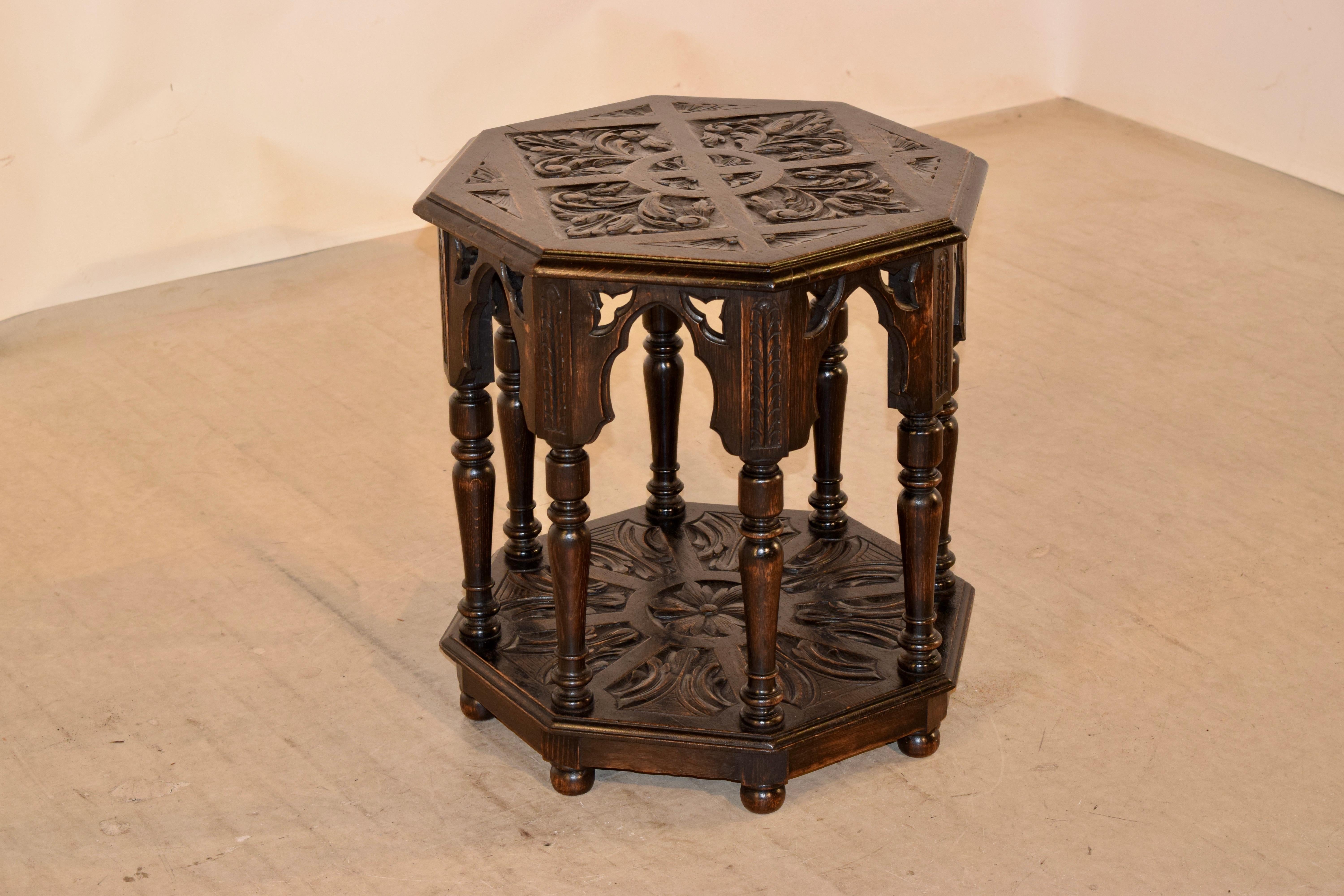19th century English oak side table with a wonderfully hand carved top surrounded by a beveled edge, following down to a scalloped Gothic molded apron and supported on eight hand turned legs, joined by a lower shelf, which is also beveled around the