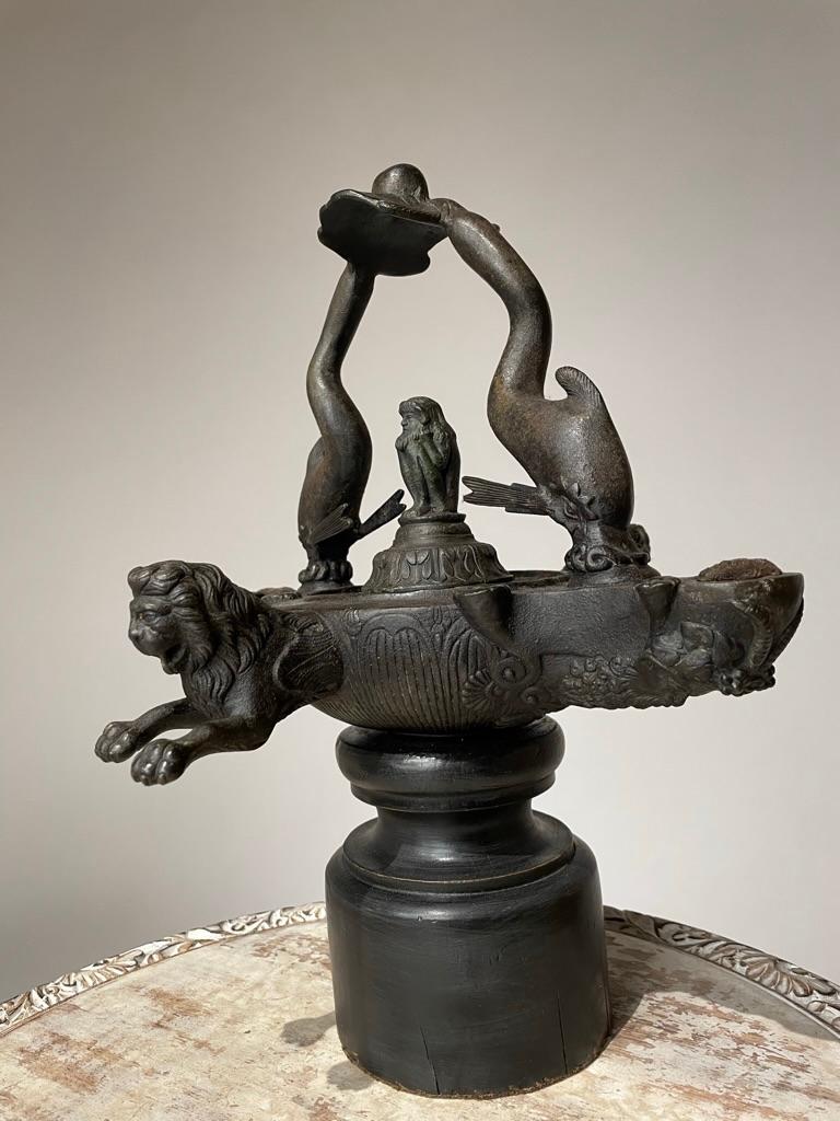 Beautifully cast and very compelling 19th century Grand Tour bronze oil lamp in the ancient Roman style with dolphin handles. The dolphin shown attacking an octopus on a rock! Decorated with lions protruding from either side, the lamp holders in the