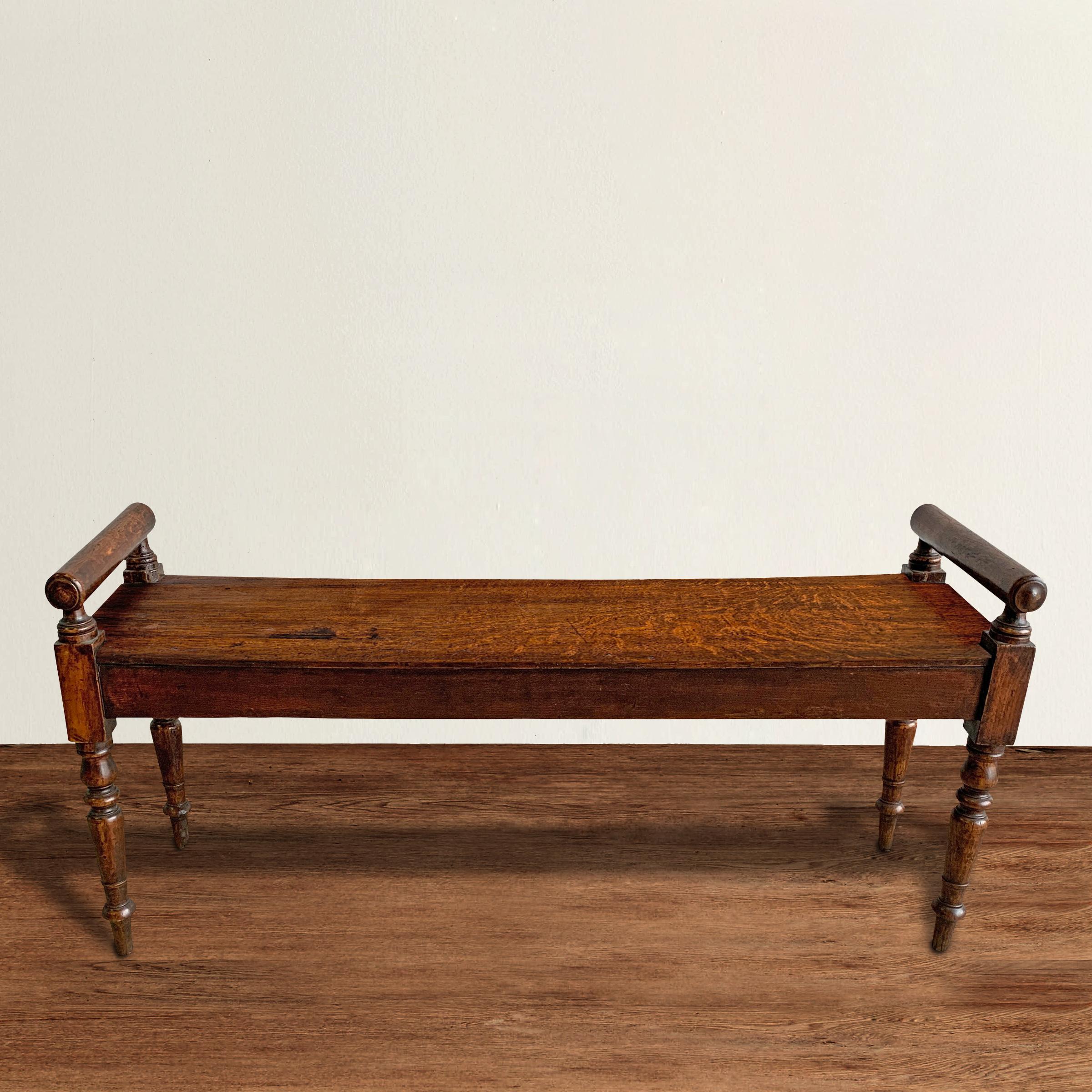 A steadfast and faithful 19th century English oak hall bench with rolling-pin turned sides, and beautifully turned and tapered legs, retaining its original patinated finish only one hundred and fifty years can bestow.