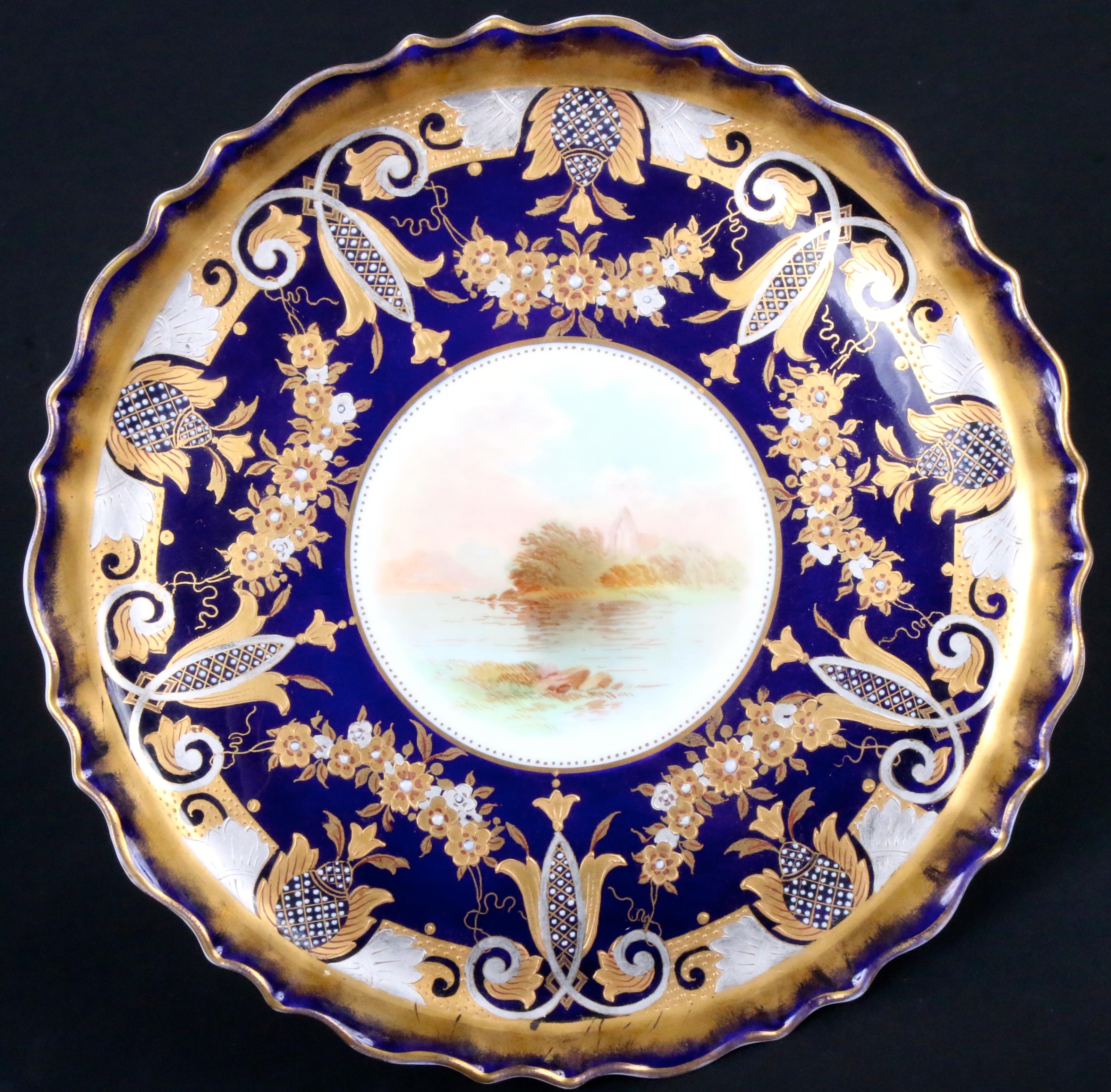 19th Century hand-painted dessert service by Bishop & Stonier, Hanley, Stafforshire, England. The set is composed of a tazza or compote and 10 dessert plates. The set has a cobalt blue background and is elaborately gilded in both yellow and white