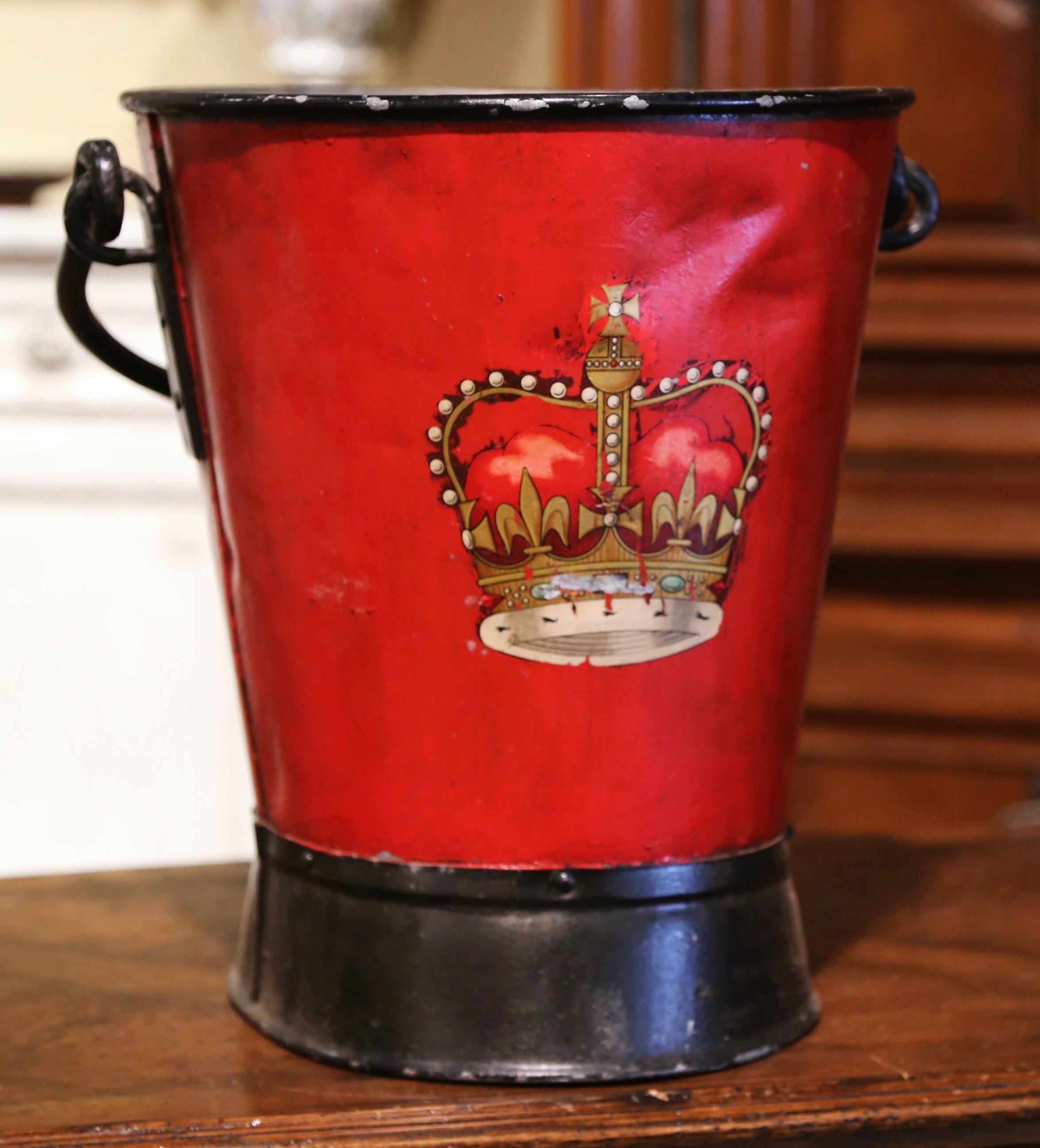 Place this large, colorful antique stand at your front door or in your mudroom to collect umbrellas, canes or other accessories. Created in England, circa 1890, the iron bucket with top and side handles, is decorated with a coat of arms with crown
