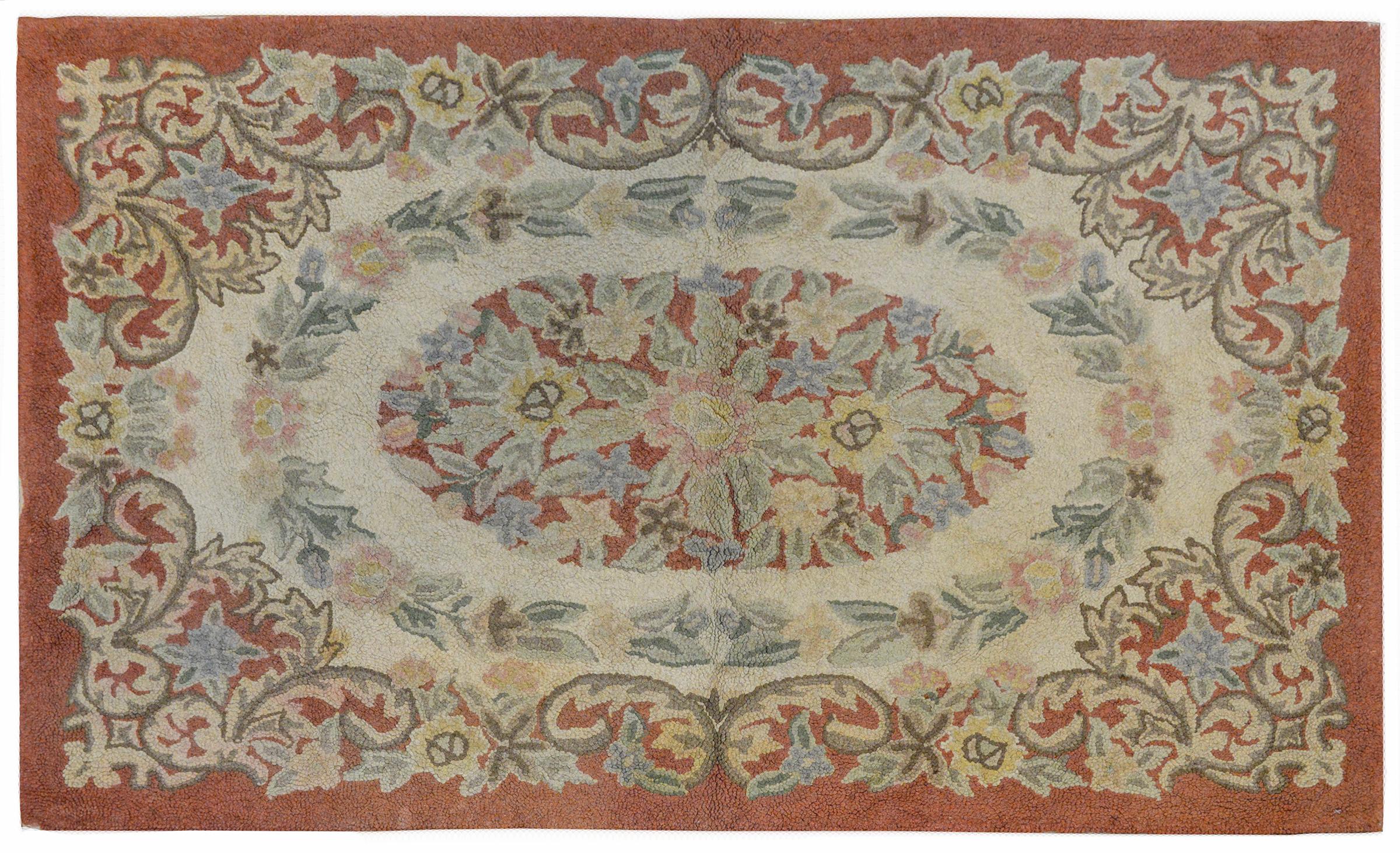 A beautiful 20th century Chinese hook rug with a wonderful floral pattern arranged in multiple ovals and rings of flowers and leaves, all woven in muted indigos, greens, yellows, and pinks on a muted red ground.
