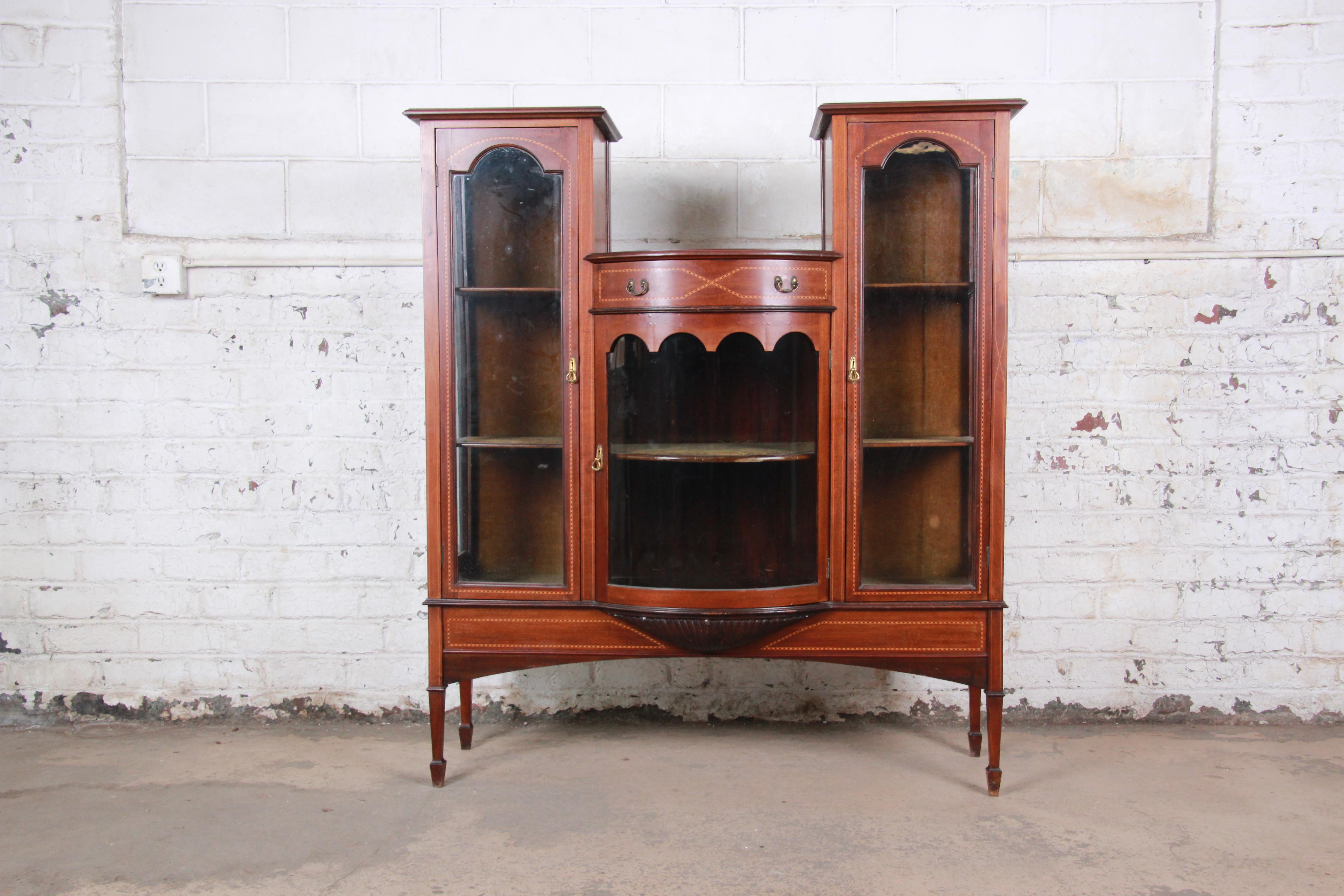 A beautiful antique inlaid mahogany curved glass curio china display cabinet or bookcase

England, late 19th century

Inlaid mahogany, glass, velvet and brass

Measures: 51.25