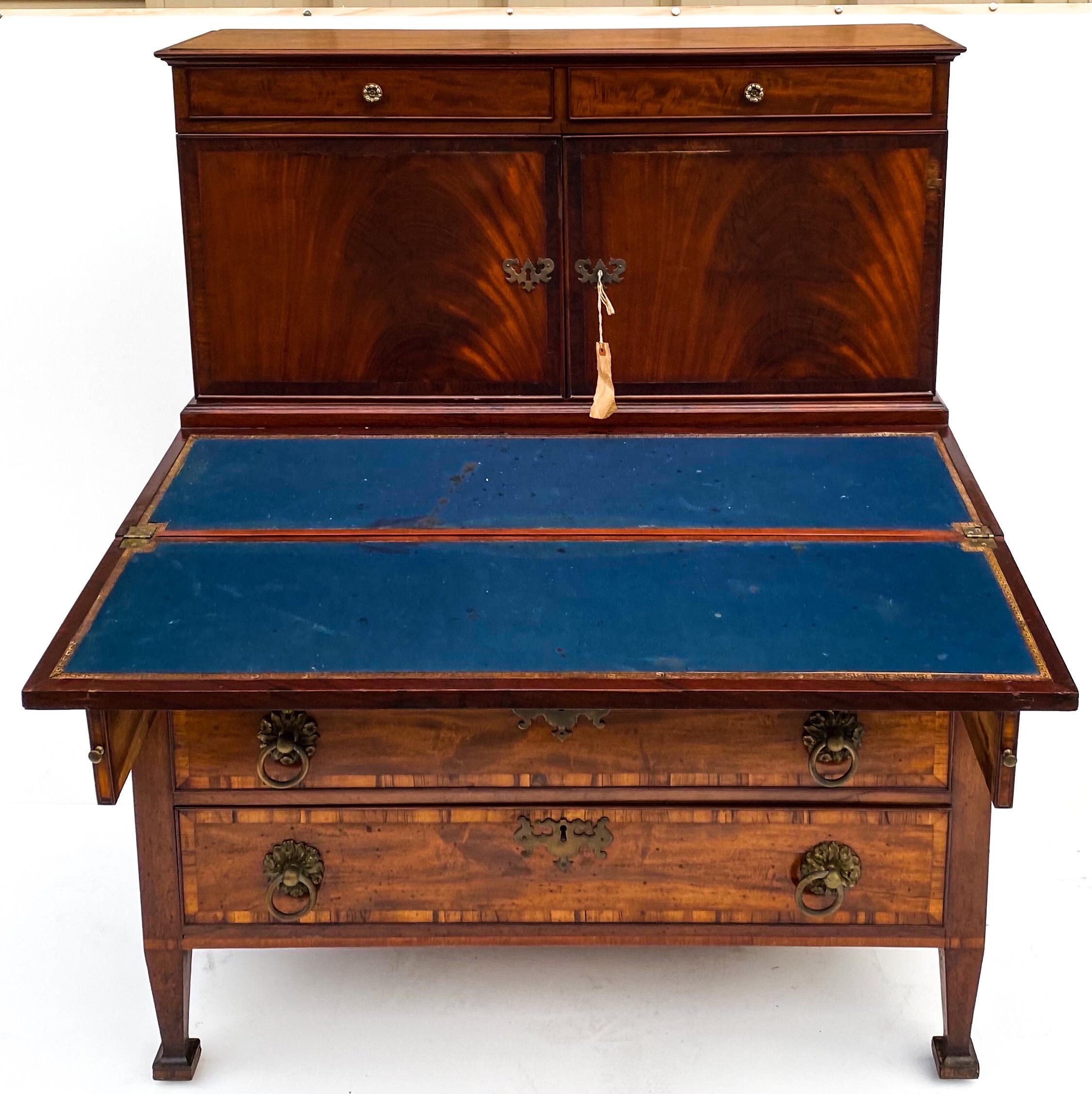 This is a 19th century English Sheraton style writing desk with mahogany and satinwood inlay. The door fronts are flame mahogany and open to storage. The three drawers have wonderful inlay, dovetail construction and original hardware. The piece