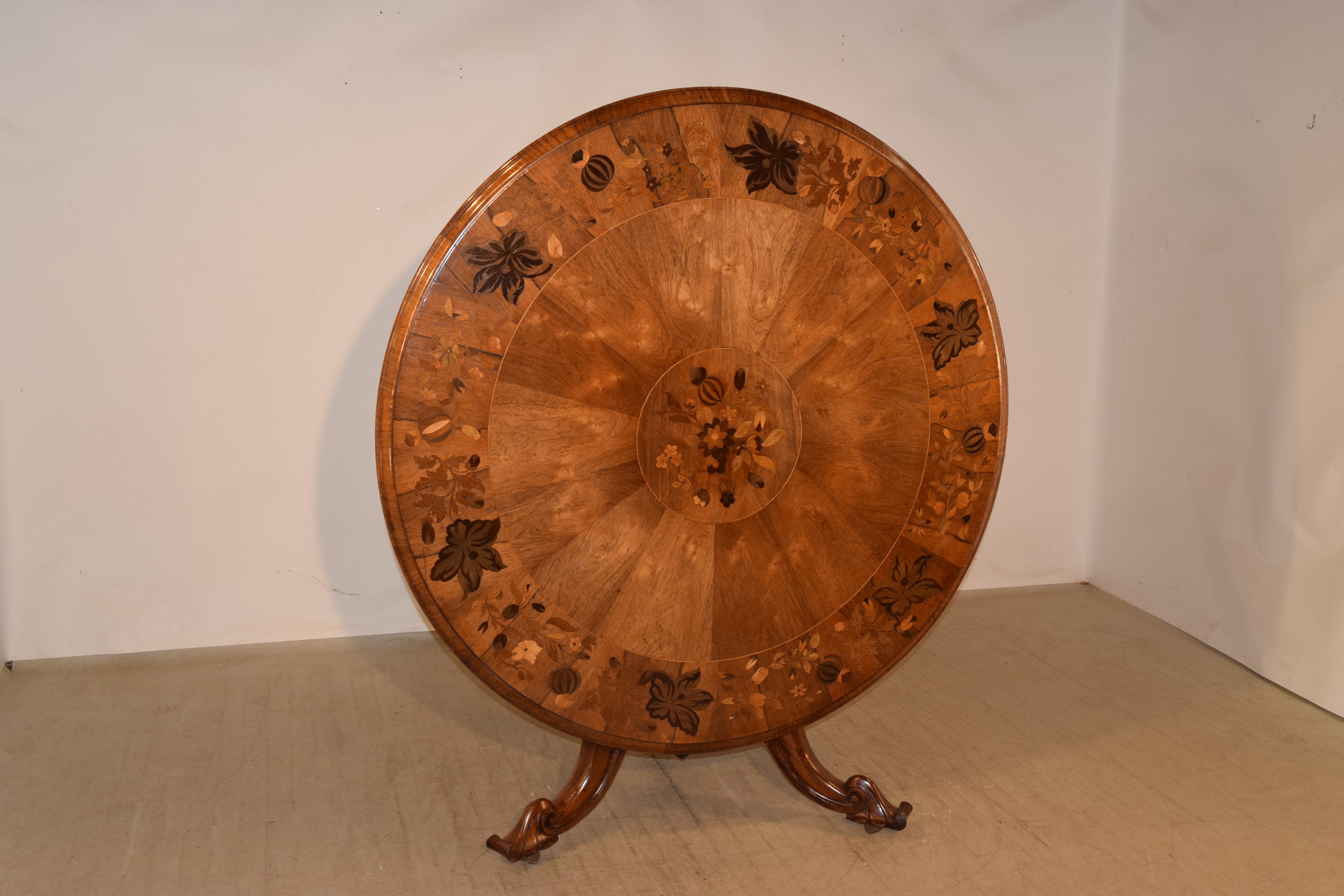 19th century tilt-top table from England made from mahogany and rosewood. The top has a beveled edge around a band of rosewood with inlaid patterns of florals, vines and fruits. The inlay work is absolutely exquisite. The rosewood band has an inner