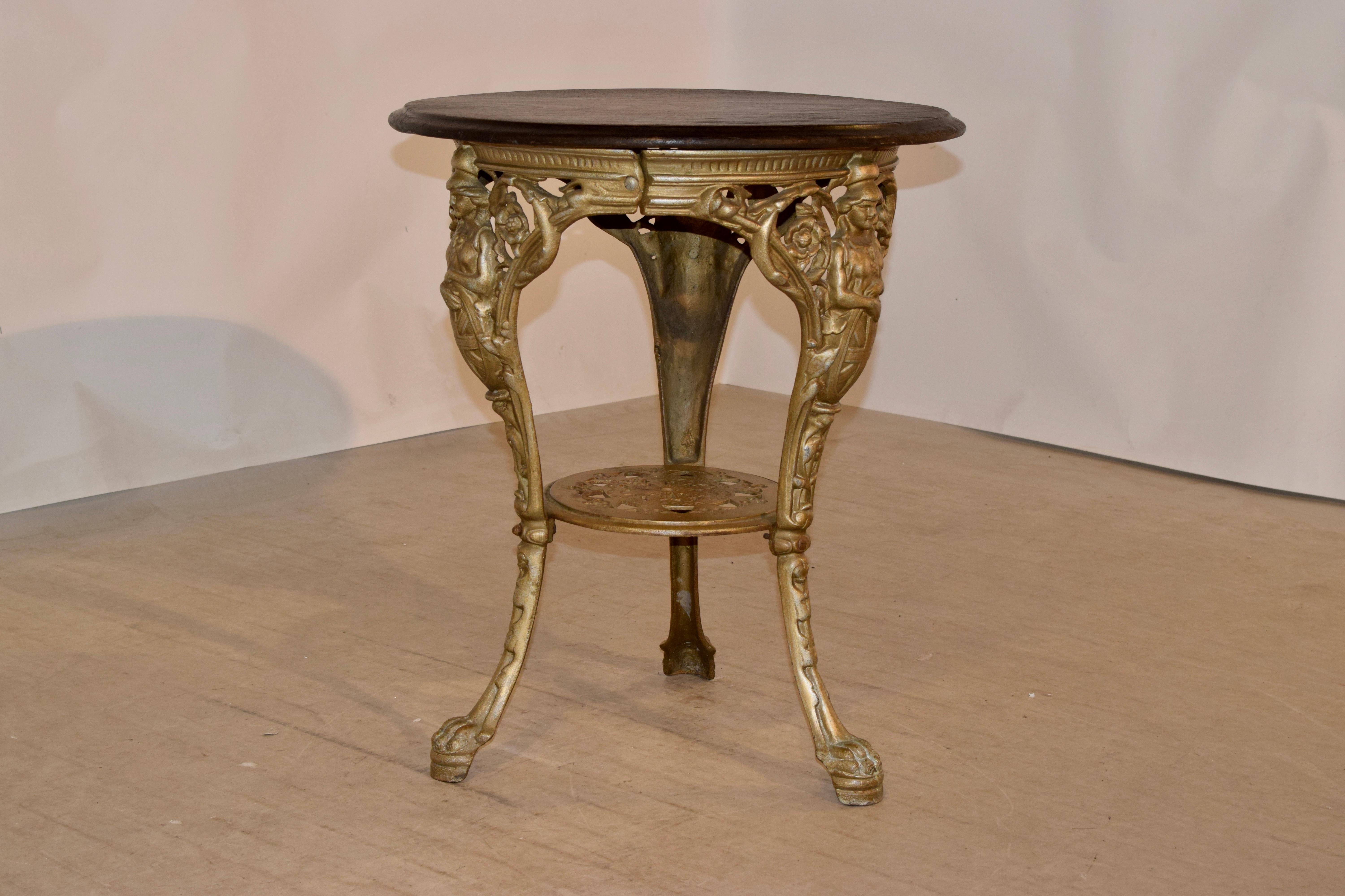 19th century English tables with iron base and mahogany top with a beveled edge around the top. The legs of the table have Brittania over the shields of England, and the legs end in paws.