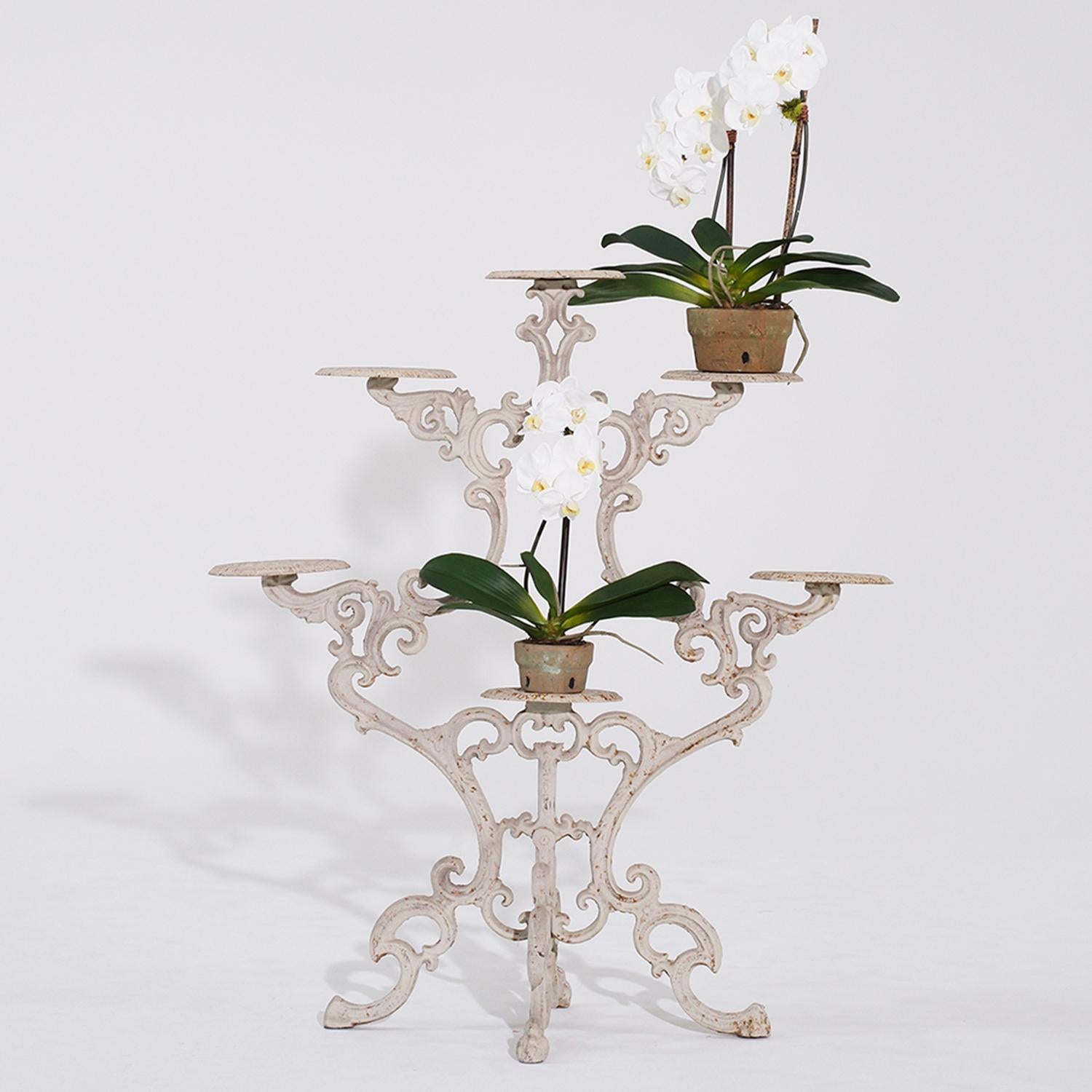 An antique Victorian period six pot plant holder in white painted cast iron with perforated plates, in good condition. Geometrical decoration on scroll cast iron frame adorned by foliage set a four legged base. Minor fading, scratches due to age.