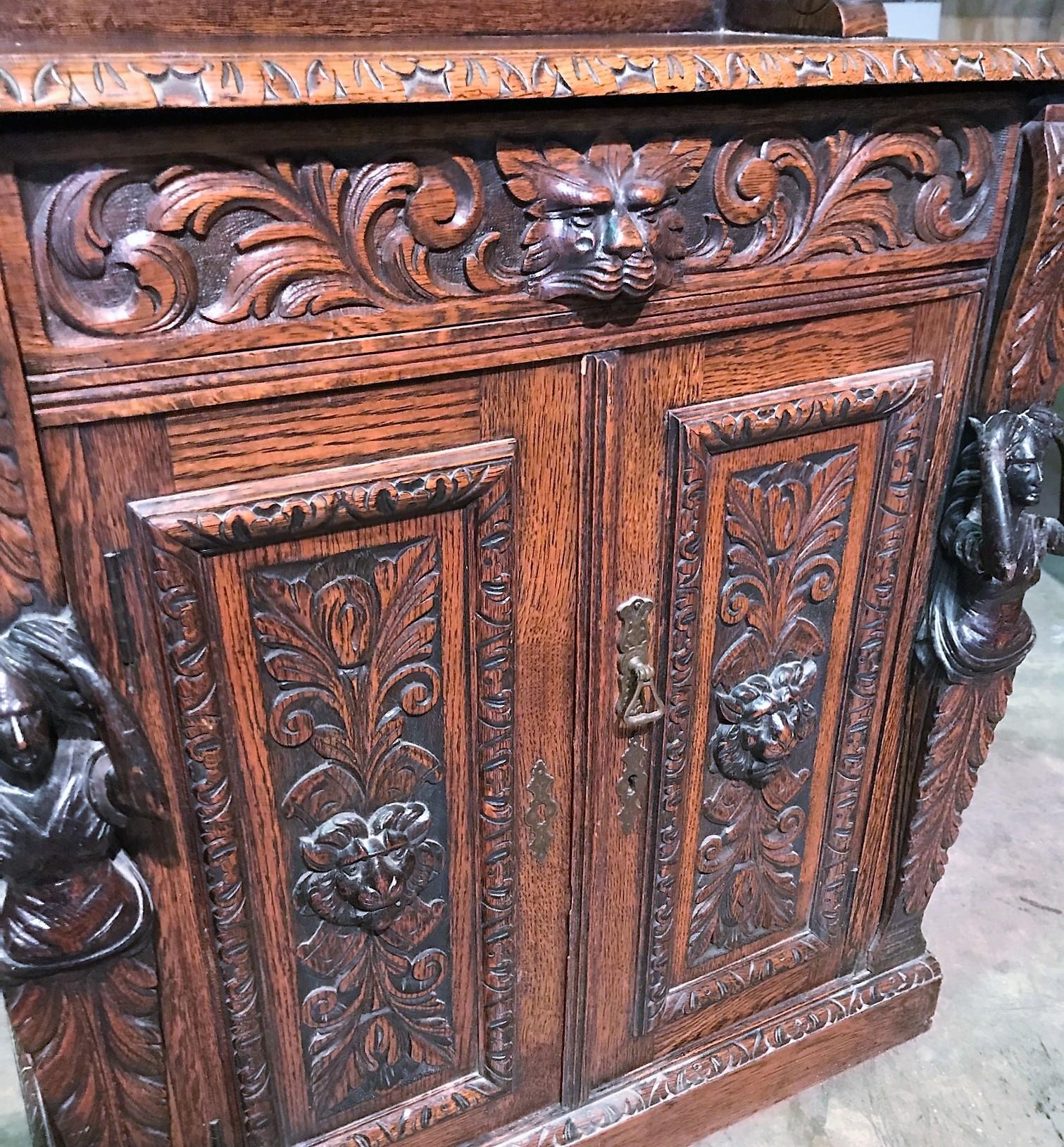 Fine quality 19th century English Jacobean style oak cabinet. The carved cornice above an inset mirror and shelf flanked by figural columns in haut-relief and accented with acanthus leaves. Possessing lion's masque carvings and complementing figural