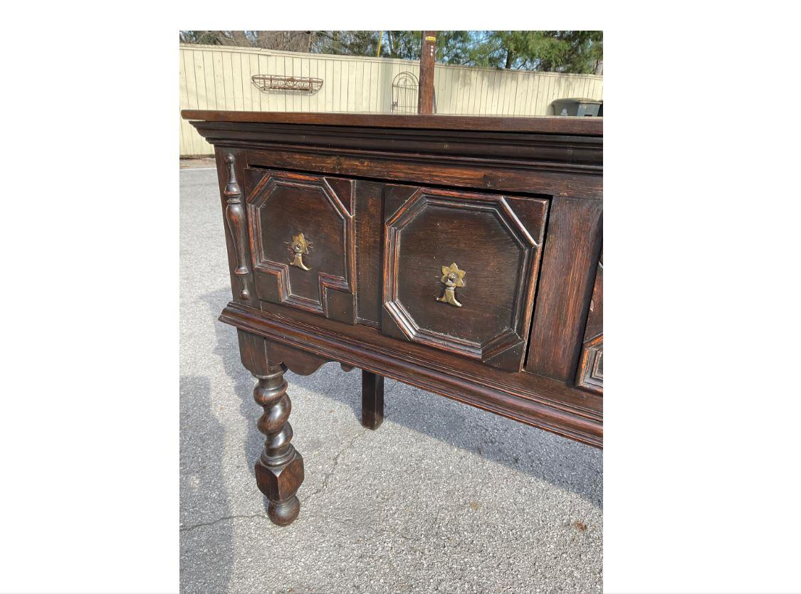 This amazing English server has such an aura of old-world charm about it. It is from the Jacobean period, dating to the 1800s, and has an excellent patina. The server has gorgeous, large, twisted legs and beautifully done geometric drawer fronts