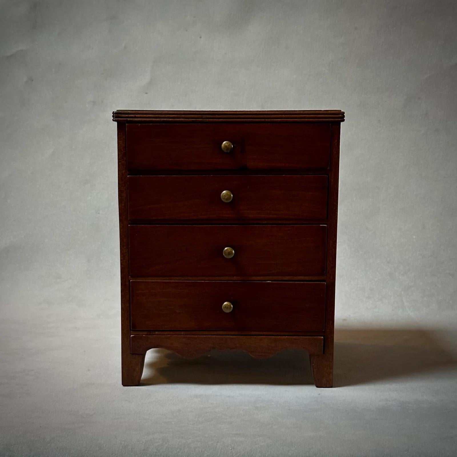 Cette exquise boîte à bijoux en bois de l'Angleterre victorienne incarne l'artisanat classique avec son couvercle carré et sa jupe biseautée. Chacun de ses quatre tiroirs est orné d'une petite poignée ronde en laiton, apportant une touche d'élégance