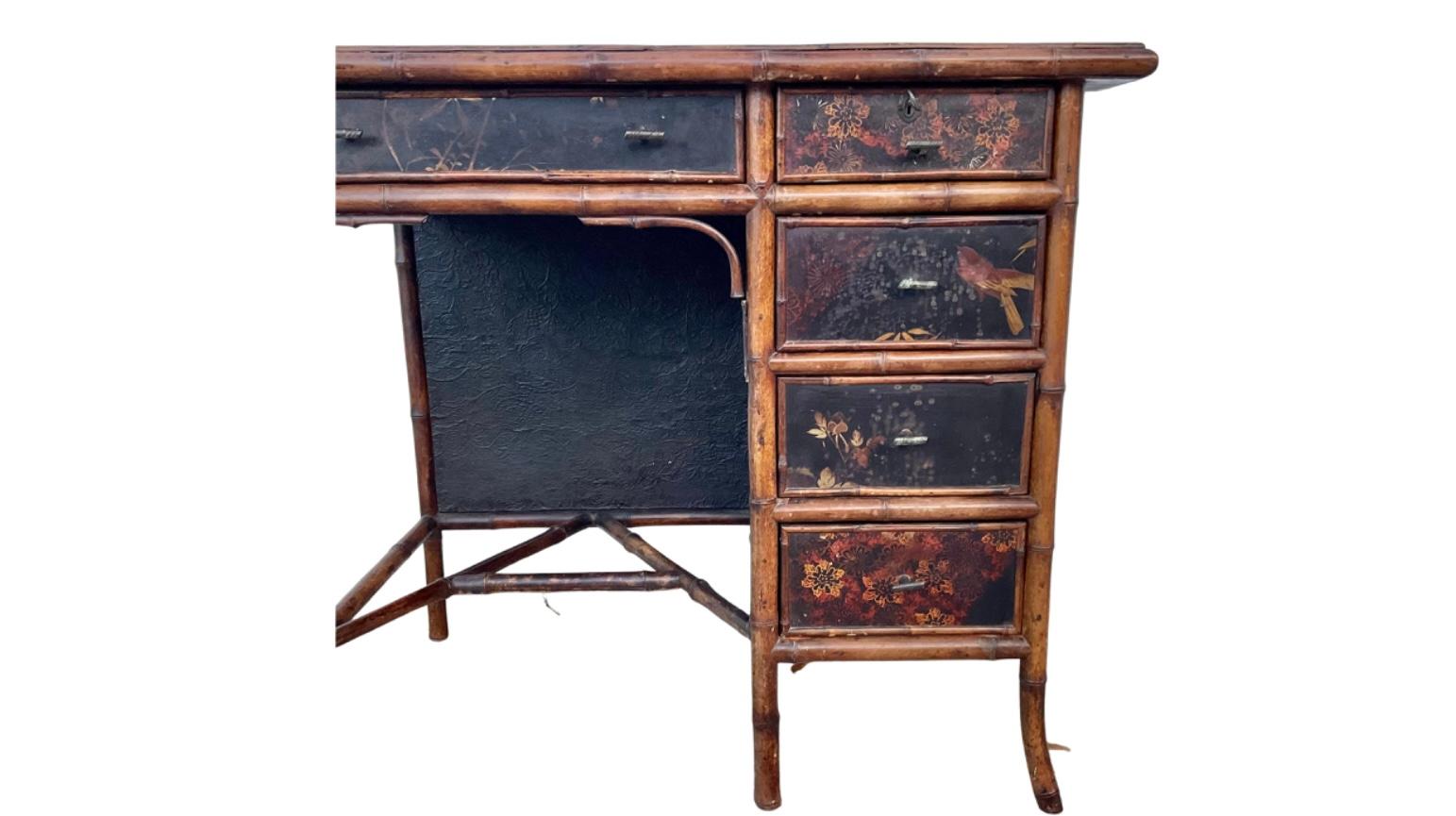 19th century lacquered bamboo writing desk with tooled leather writing surface decorated in the Chinoiserie style. Decorated in the birds and floral fashion of the style. Features five pull-out drawers with bamboo shape handles. 