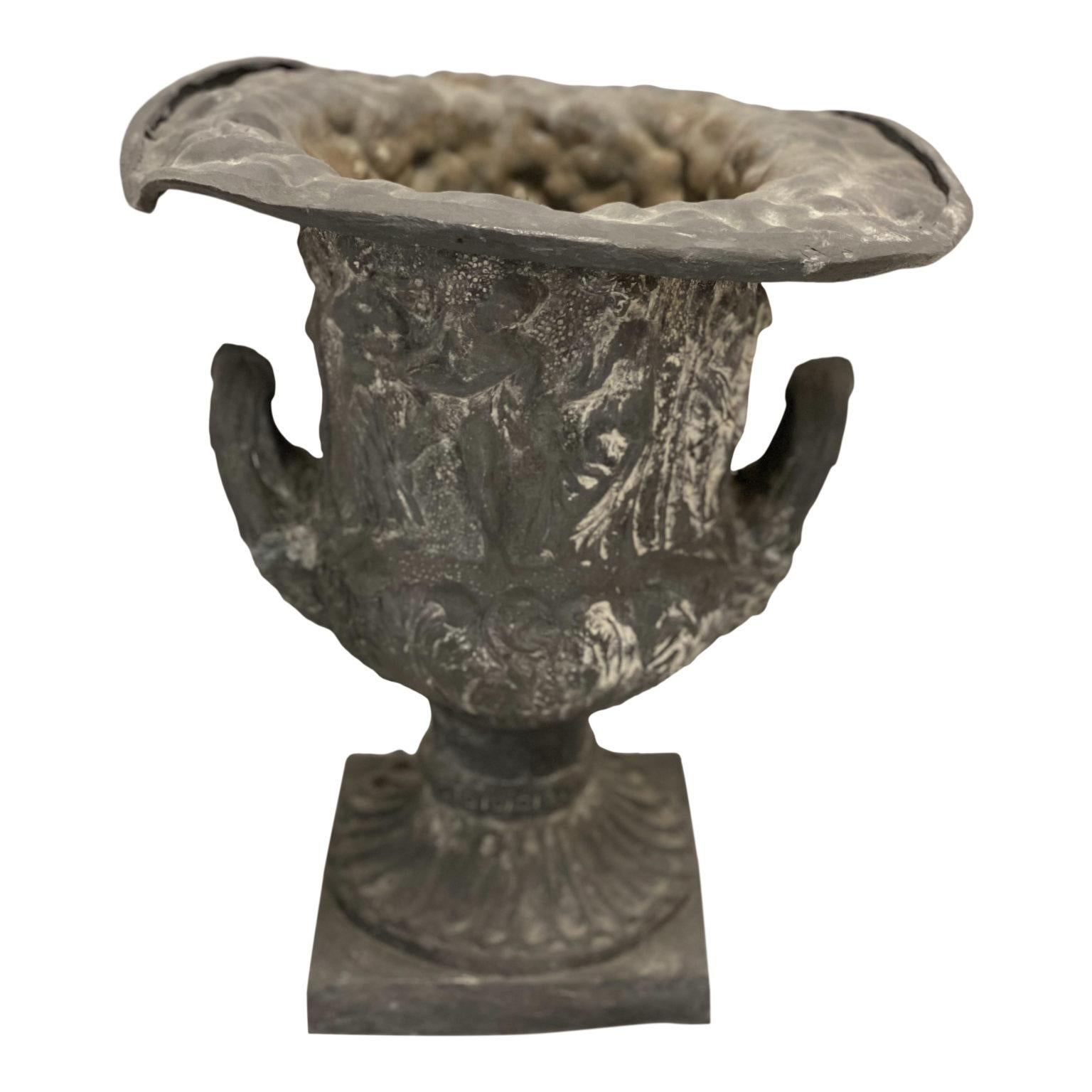Une ancienne urne du 19ème siècle de forme classique, avec des poignées doubles et des figures encerclant le corps.

Pliée et bosselée

16″H, Base carrée 8″, OAD 15.25″