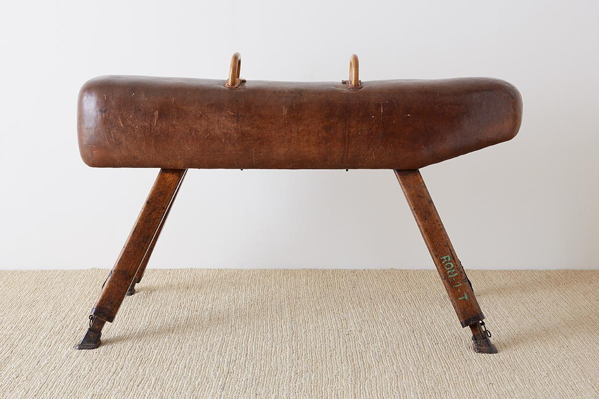 Fantastic 19th century English leather gymnastic pommel horse or bench. Features a beautiful, rich patina on the leather and antique wood. The leather is complete and pliable with padding. The pommel is supported by adjustable iron legs ending with