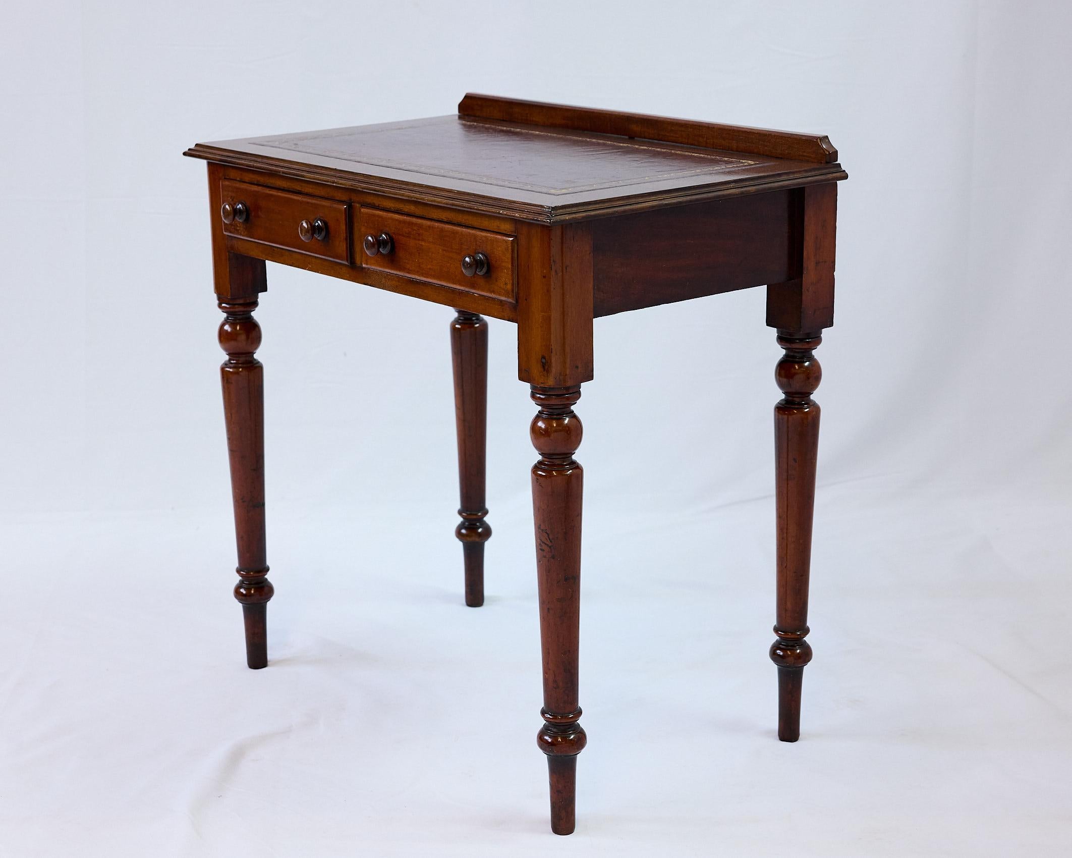 Late 19th Century English rectangular writing table or desk beautifully constructed of mahogany in the Regency style. On its top, the table features a short molded gallery along the back edge (to prevent roll-offs) with the surface inset with a fine