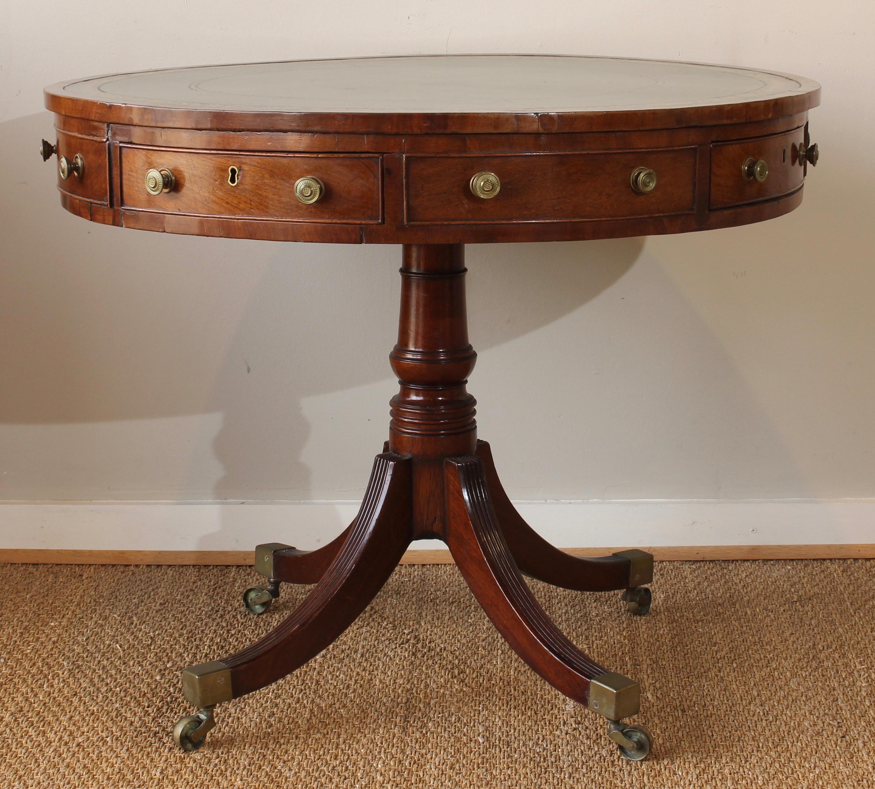 An elegant mid-19th century. English mahogany drum table of small scale with green tooled leather inset top above four working and four false drawers resting on a beautifully turned pedestal and reeded legs terminating in brass capped casters.