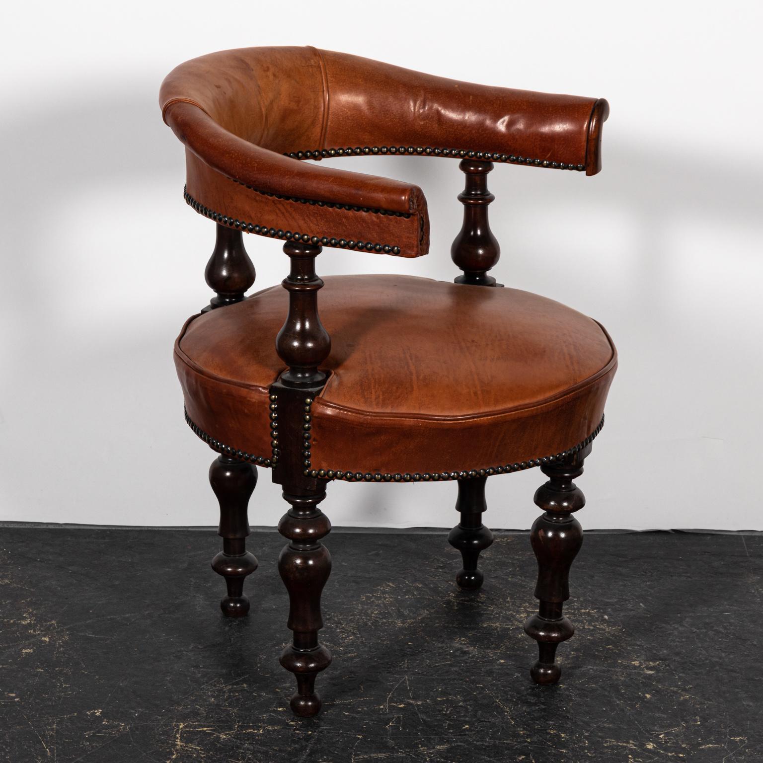 English leather upholstered desk chair with metal nail head trim and vase turned legs, circa 19th century. Please note of wear consistent with age including stains and finish loss to the leather.
