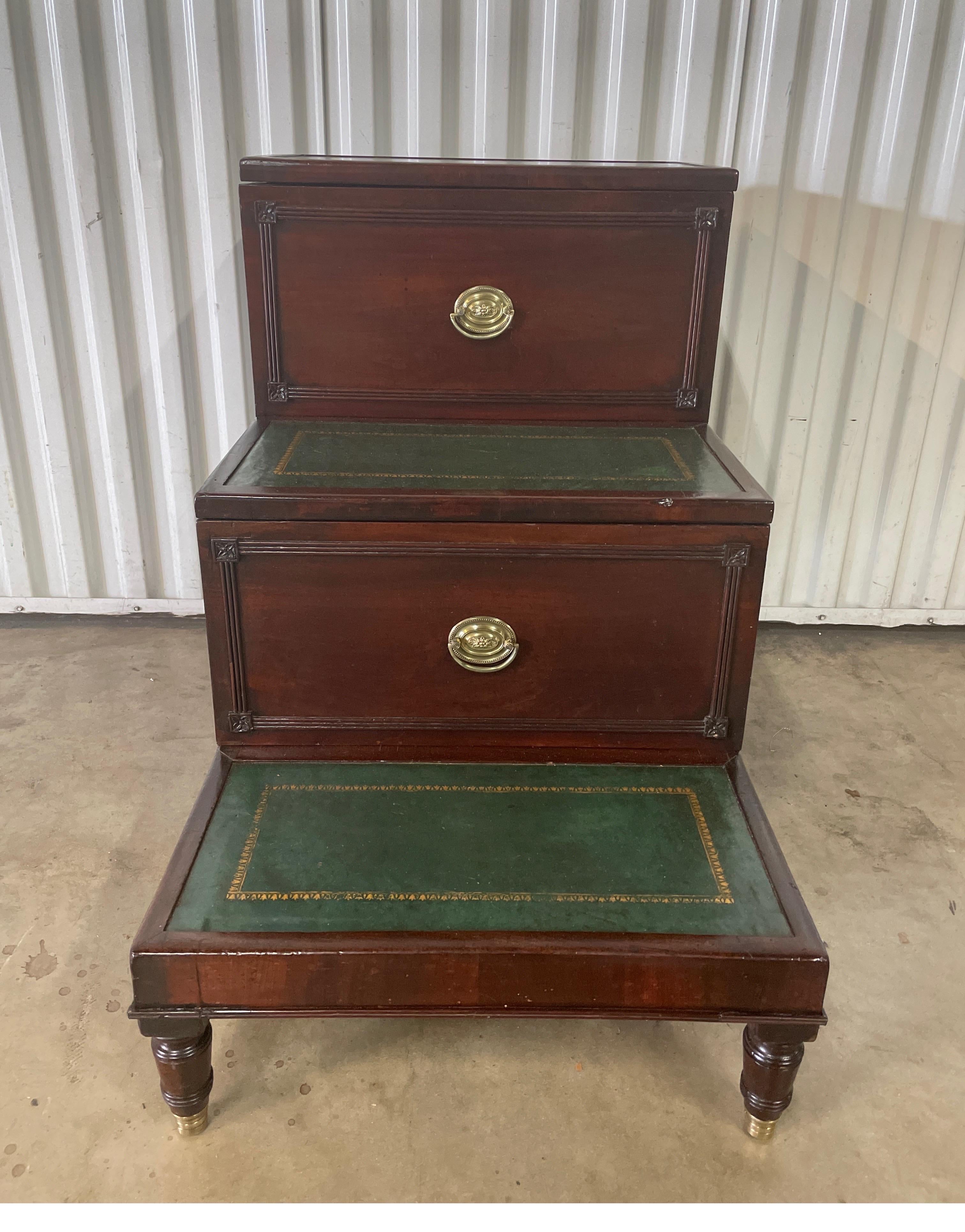 English 19th century library steps with tooled green leather steps. One drawer pulls out for storage & top step is hinged to lift up. Oval brass pulls complete this piece.