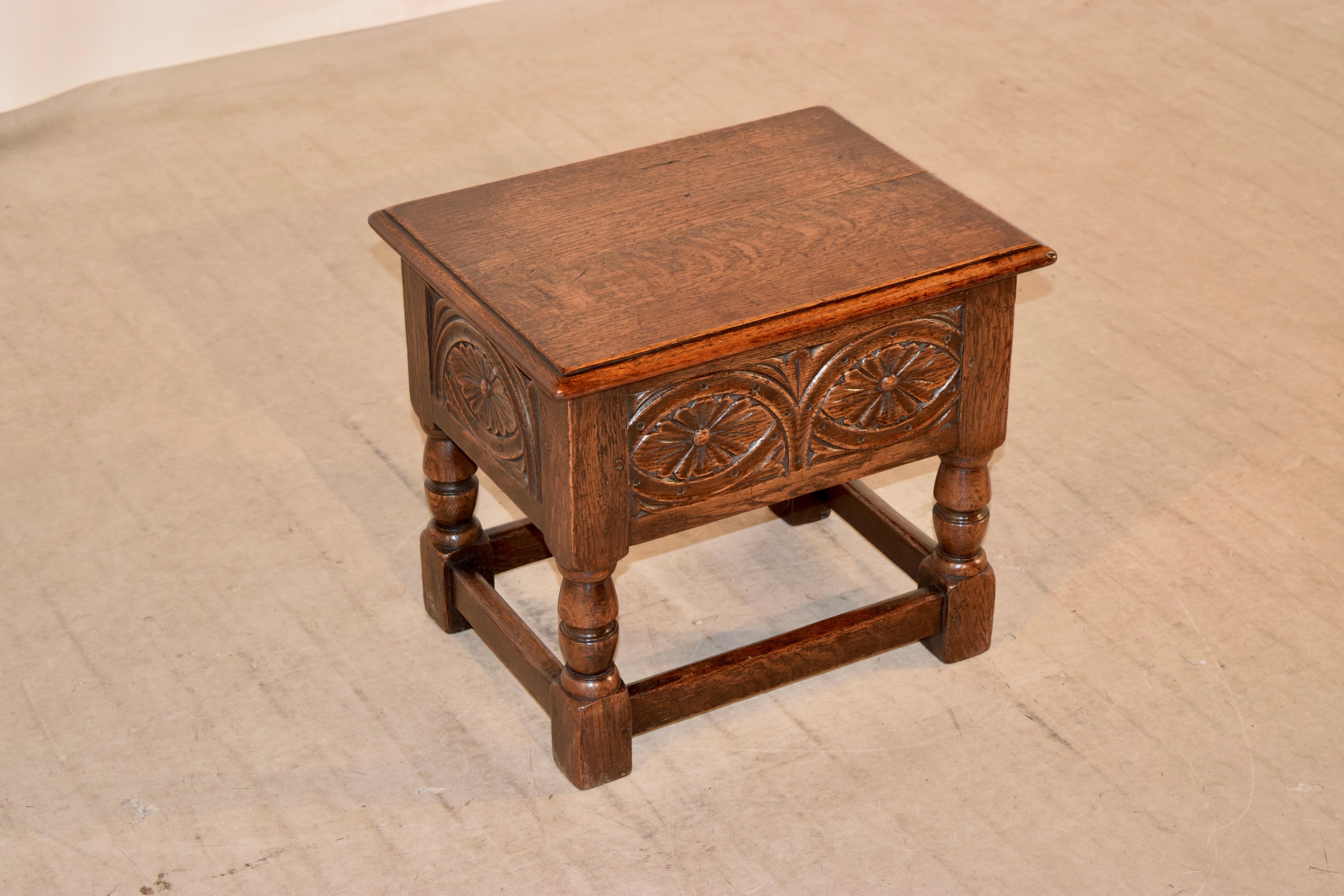 19th century lift English oak lift top stool with a beveled edge around the top following down to hand carved decorated panels on three sides and a simple panel in the back, all-over hand-turned legs joined by simple stretchers.