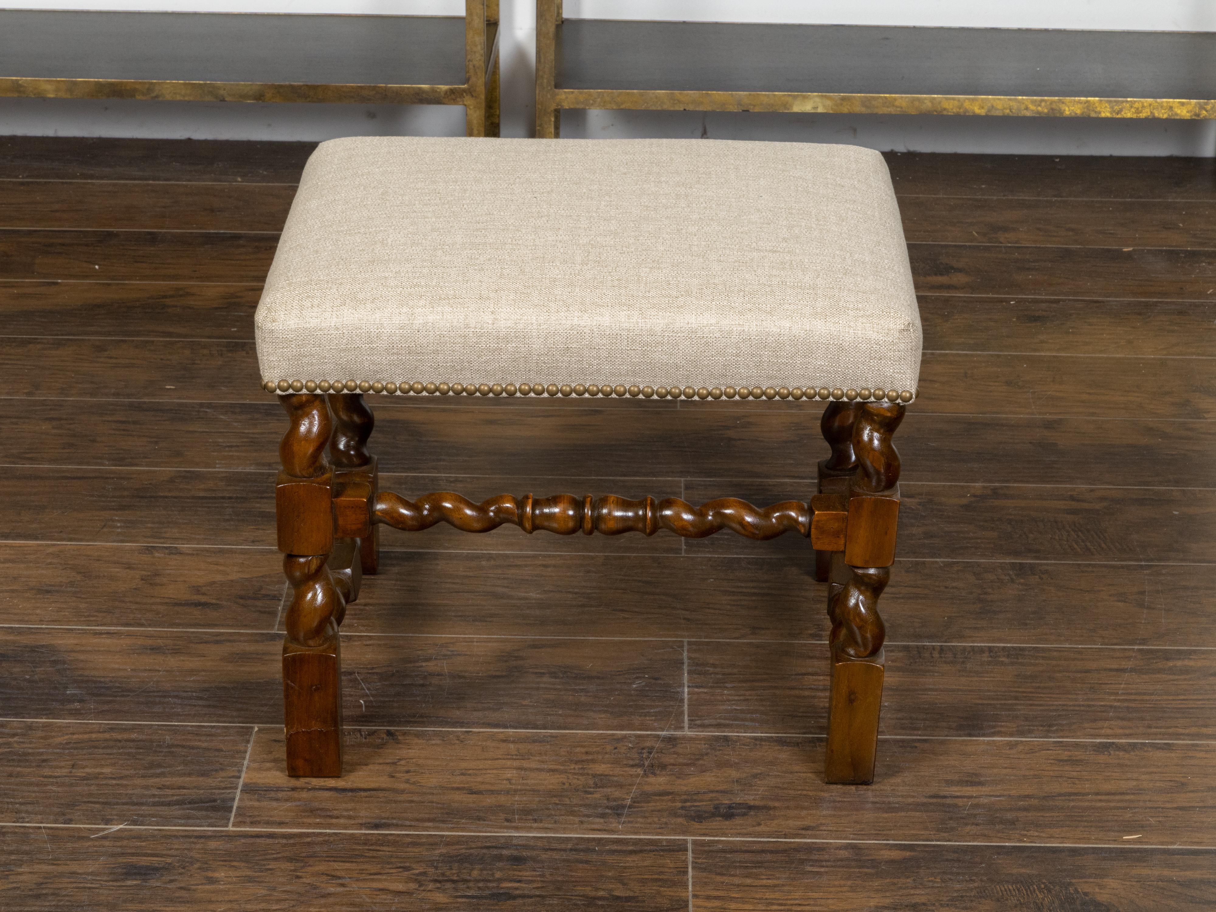 An English oak stool from the 19th century, with barley twist base, rectangular block joints, new custom made linen upholstery and brass nailhead trim. Created in England during the 19th century, this oak stool features a rectangular seat newly