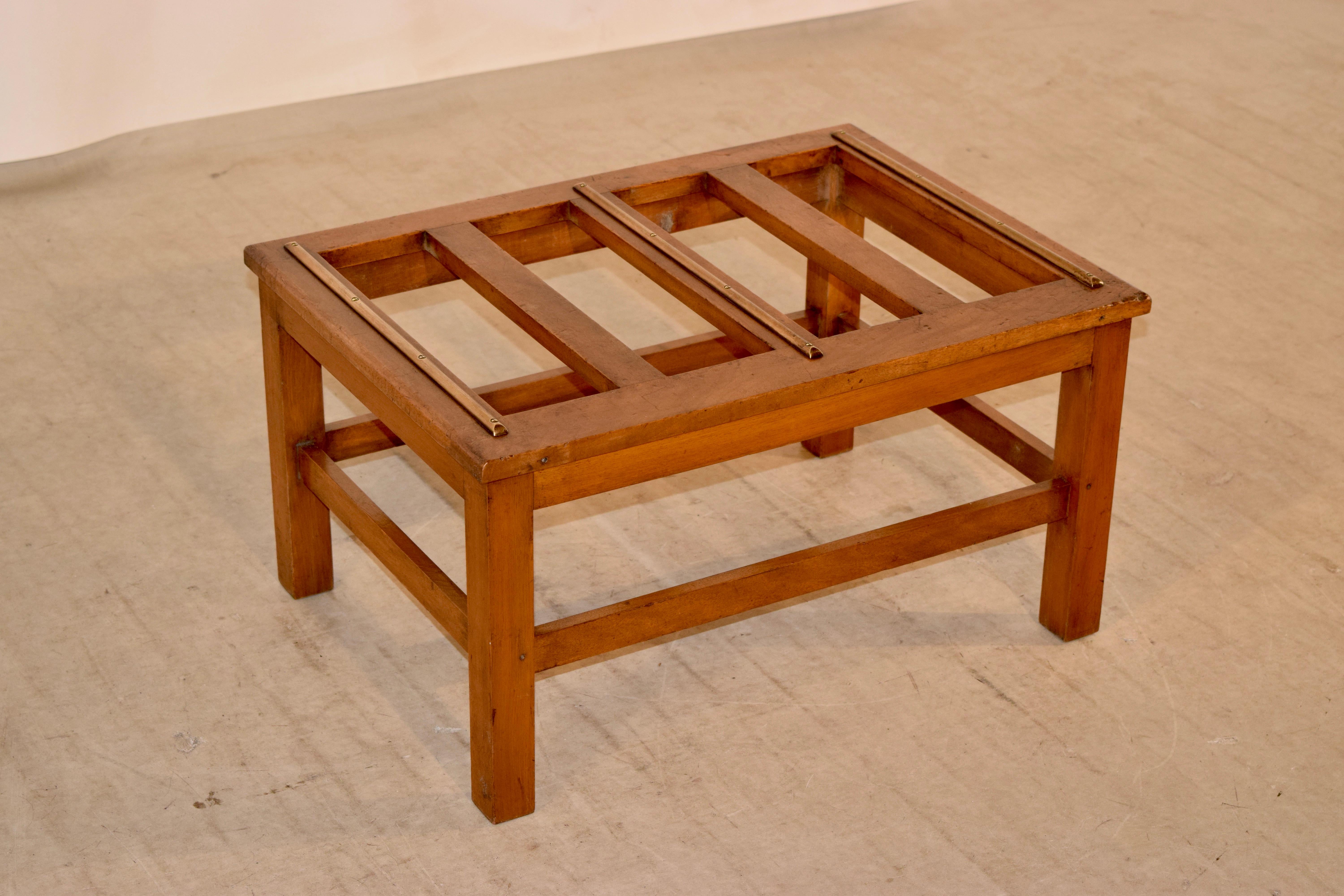 19th century luggage stand from England made from fruitwood with a slatted top which has applied brass rails. Very simple and elegant design.