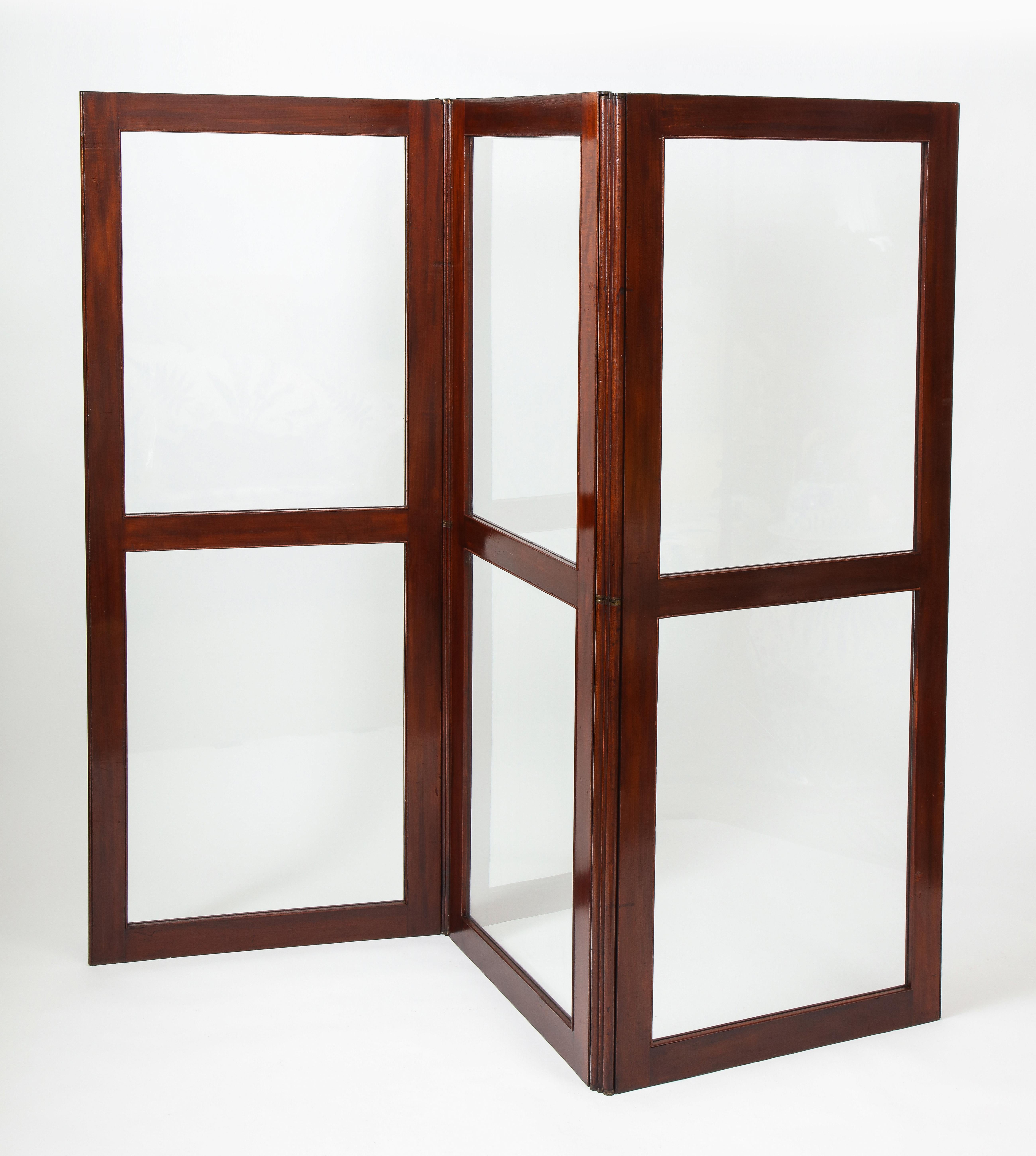 Each panel with richly hued mahogany frame enclosing clear glass, secured by brass hinges. Each panel measures: 27.25