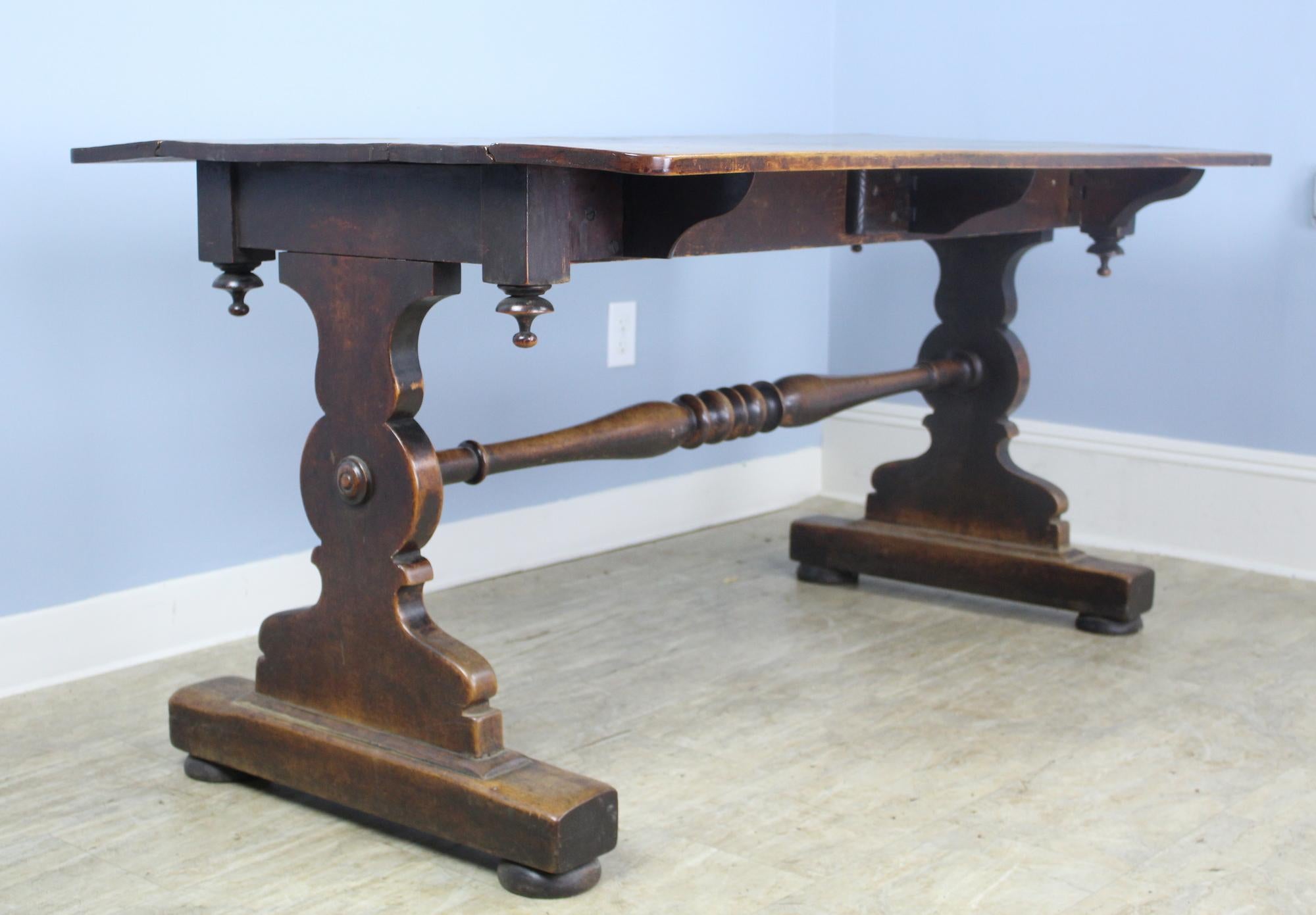 A walnut and mahogany drop leaf table, taken from a pub in Northwest England pub. The top has three supports at each drop-down side, and has a wonderful well worn patina, reflecting its generations of industrial use. The base is well carved, with