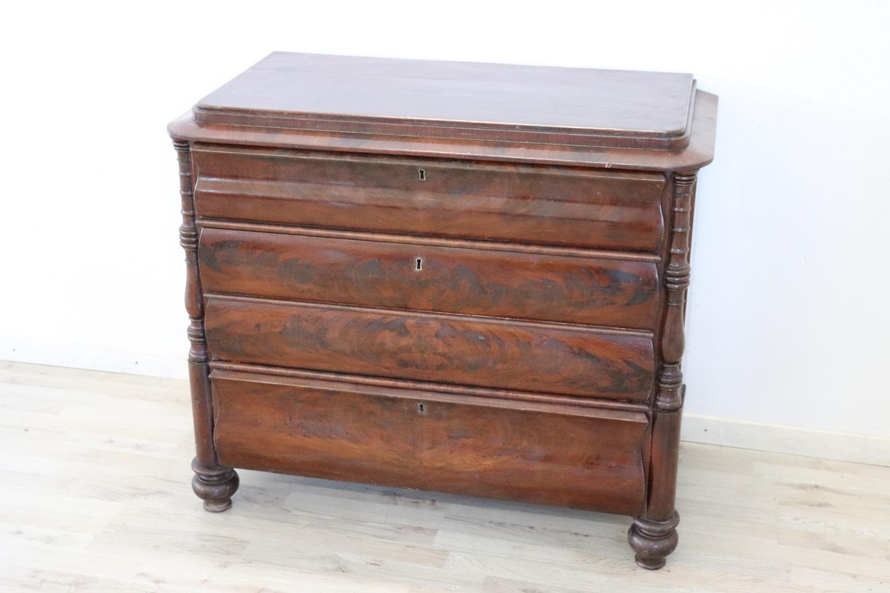 Antique English chest of drawers 1850s in mahogany wood. Very linear and essential with four comfortable drawers. On the front drawers with a particular rounded shape. At the sides on the front elegant turned decoration. It shows signs of wear at