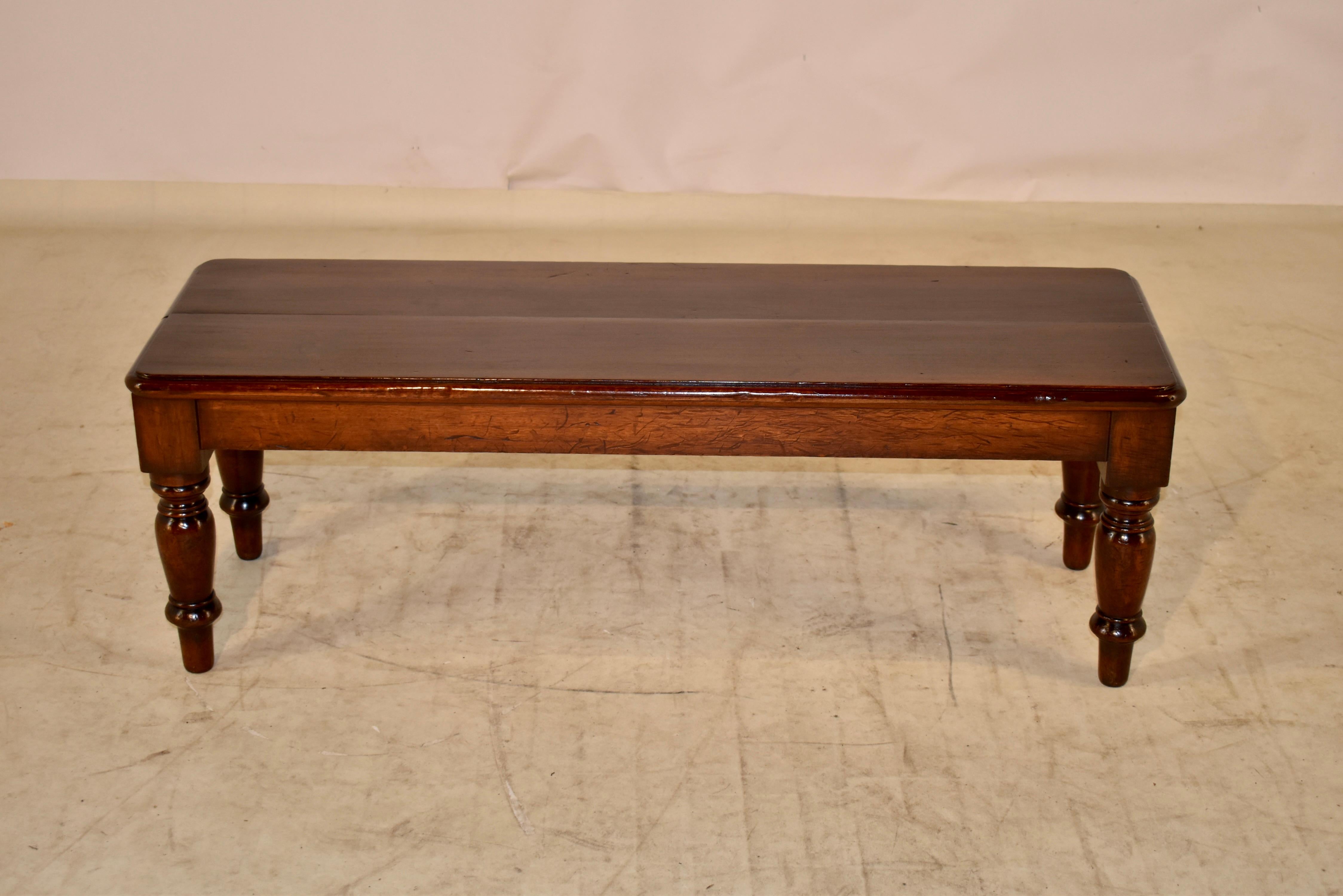 19th century mahogany bench from England.  The top is made from two boards, which are beveled along the edges for a more finished design.  The top is supported on a simple apron over hand turned legs.
