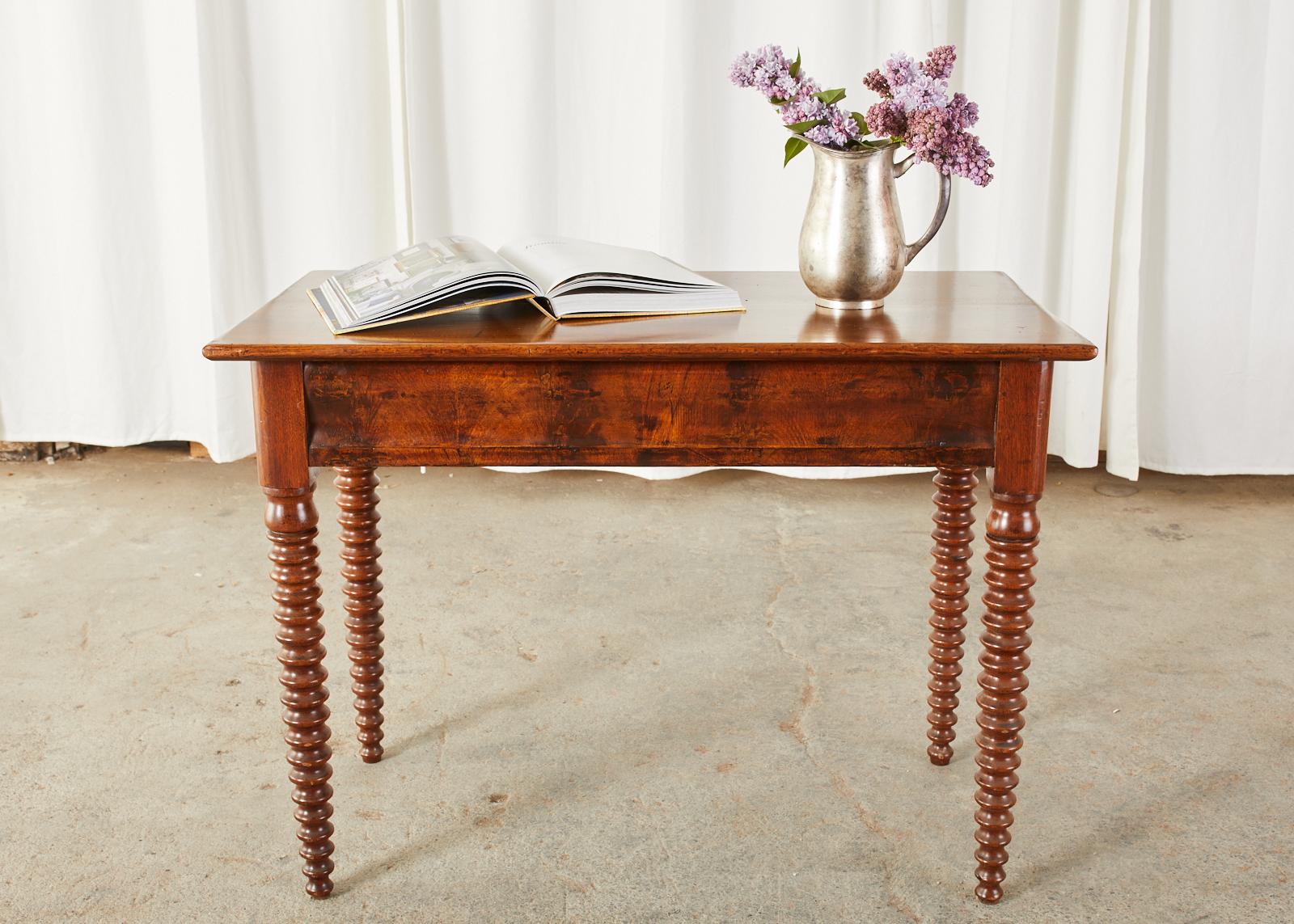 Handsome 19th century English console table, work table, or writing table made in the George IV taste. Constructed from radiant grained mahogany featuring elegant, tapered bobbin-turned legs. The case has a mahogany veneered front frieze with a