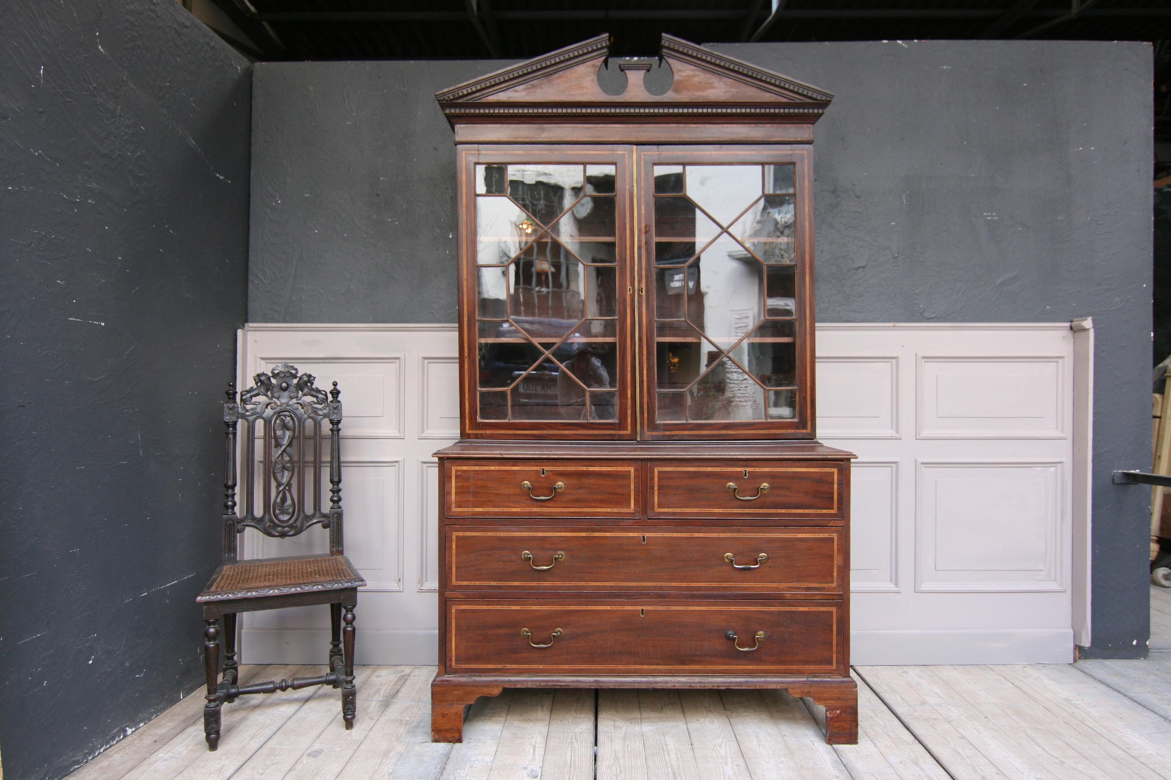 An 19th century English bookcase made with mahogany veneer and satinwood inlays. Consisting of a chest of drawers with 2 large and 2 small drawers, as well as the display case with 2 doors and a broken pediment on top. 

Dimensions:
85 or 218 cm