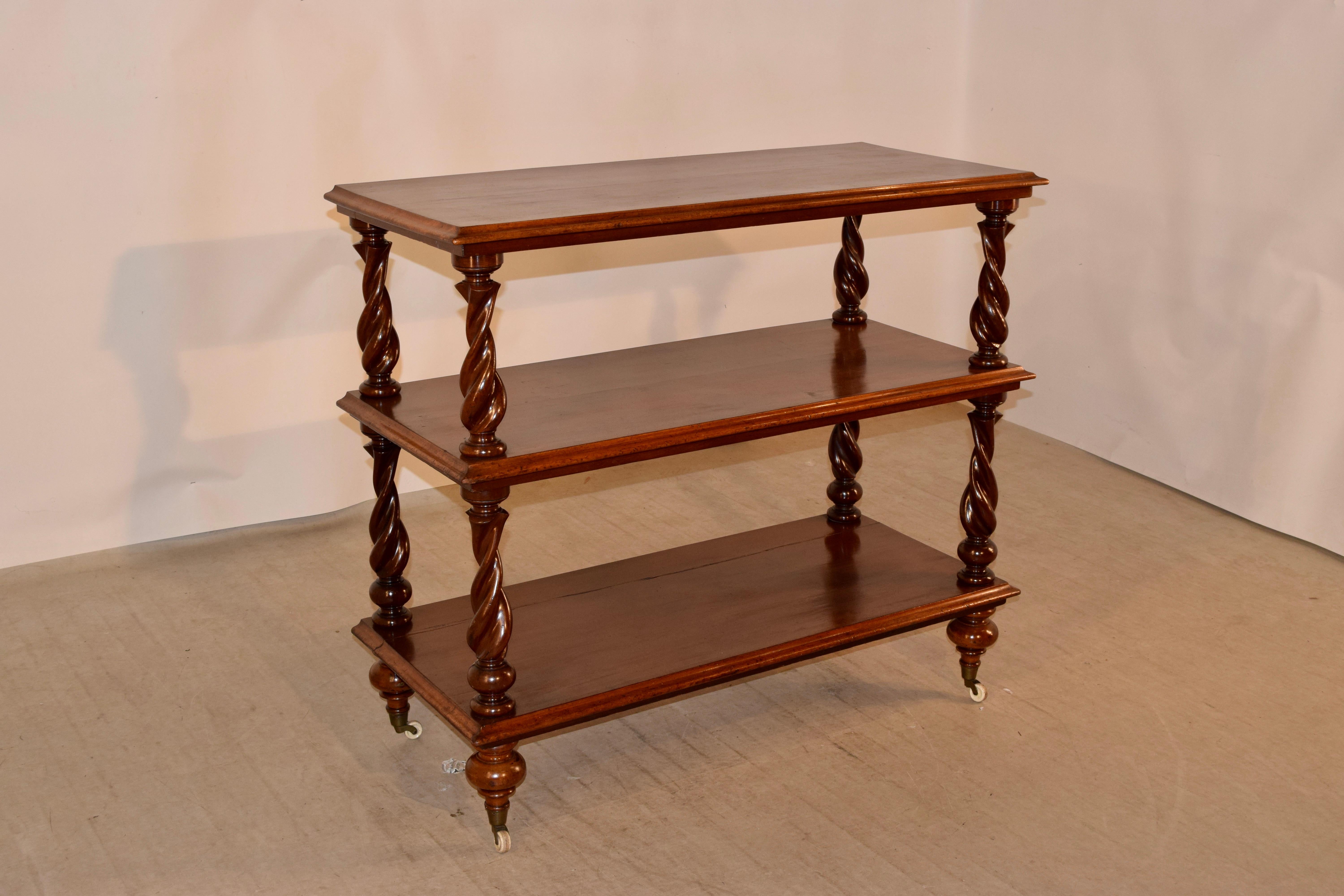 19th century mahogany buffet from England with three shelves, all with beveled edges and separated by hand-turned graduated barley twist shelf supports. The piece is supported on hand-turned feet with what appear to be the original porcelain castors.
