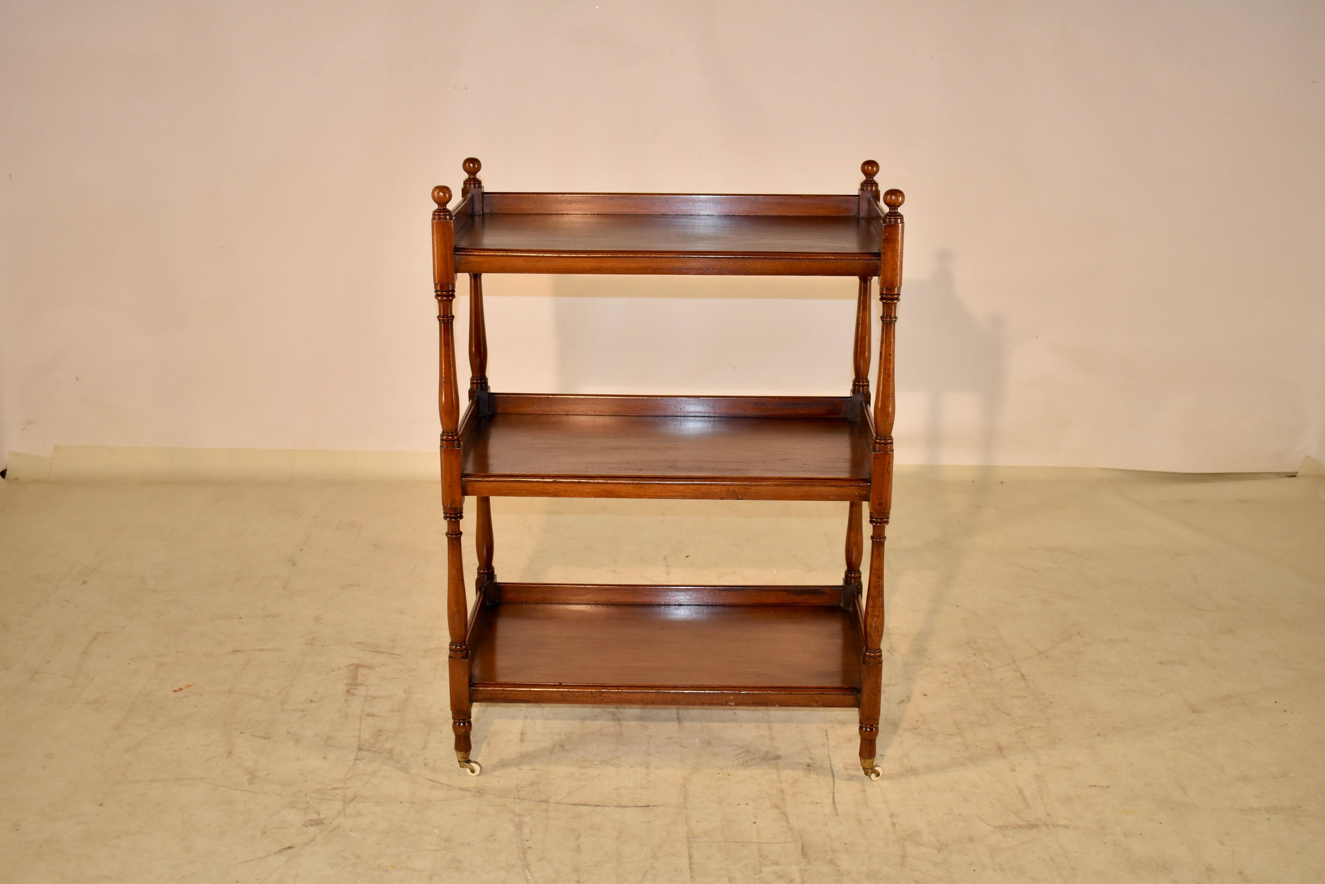 19th century mahogany buffet or shelf from England. The top has turned finials over three shelves with galleries. The shelves are separated by hand turned legs, which end in the original porcelain and brass casters. The shelves have lovely graining
