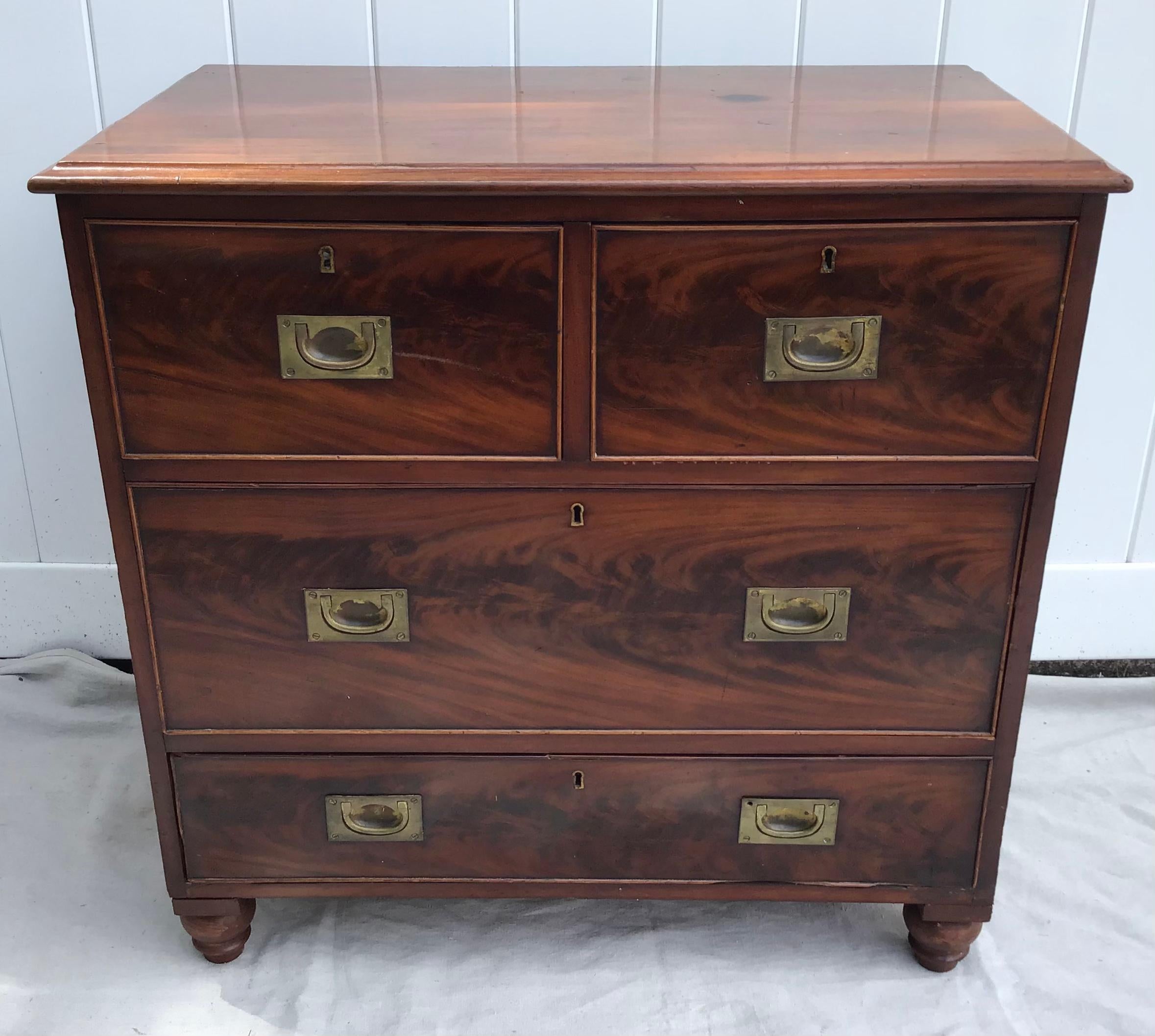 An English highly figured mahogany campaign chest from the mid-19th century, with four drawers, brass hardware and bun feet. Born in England during the 19th century, this campaign chest features a rectangular top sitting above four dovetailed