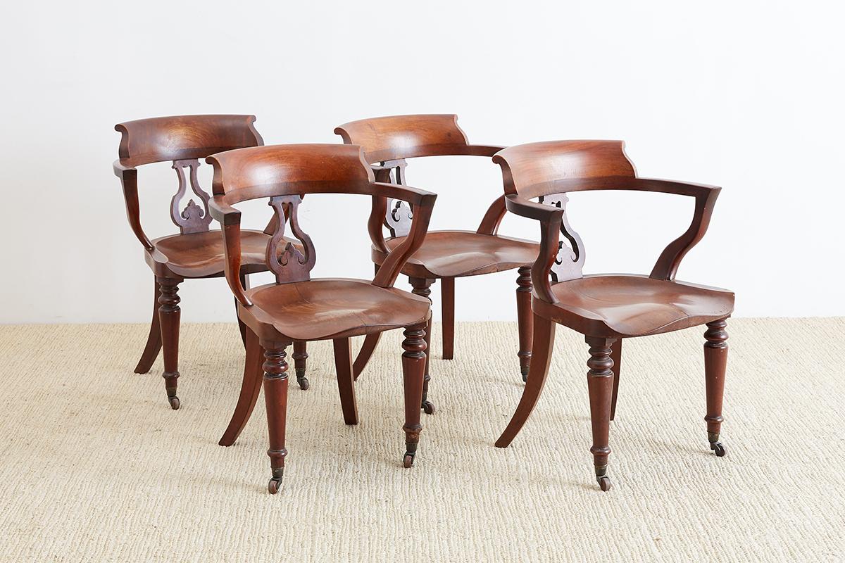 Set of four handsome English pub chairs or captain's chairs handcrafted from mahogany. Rare chairs with a shaped saddle seat and a back splat featuring a spade design. Also known as bow back chairs, Windsor chairs, and smokers chairs. Very