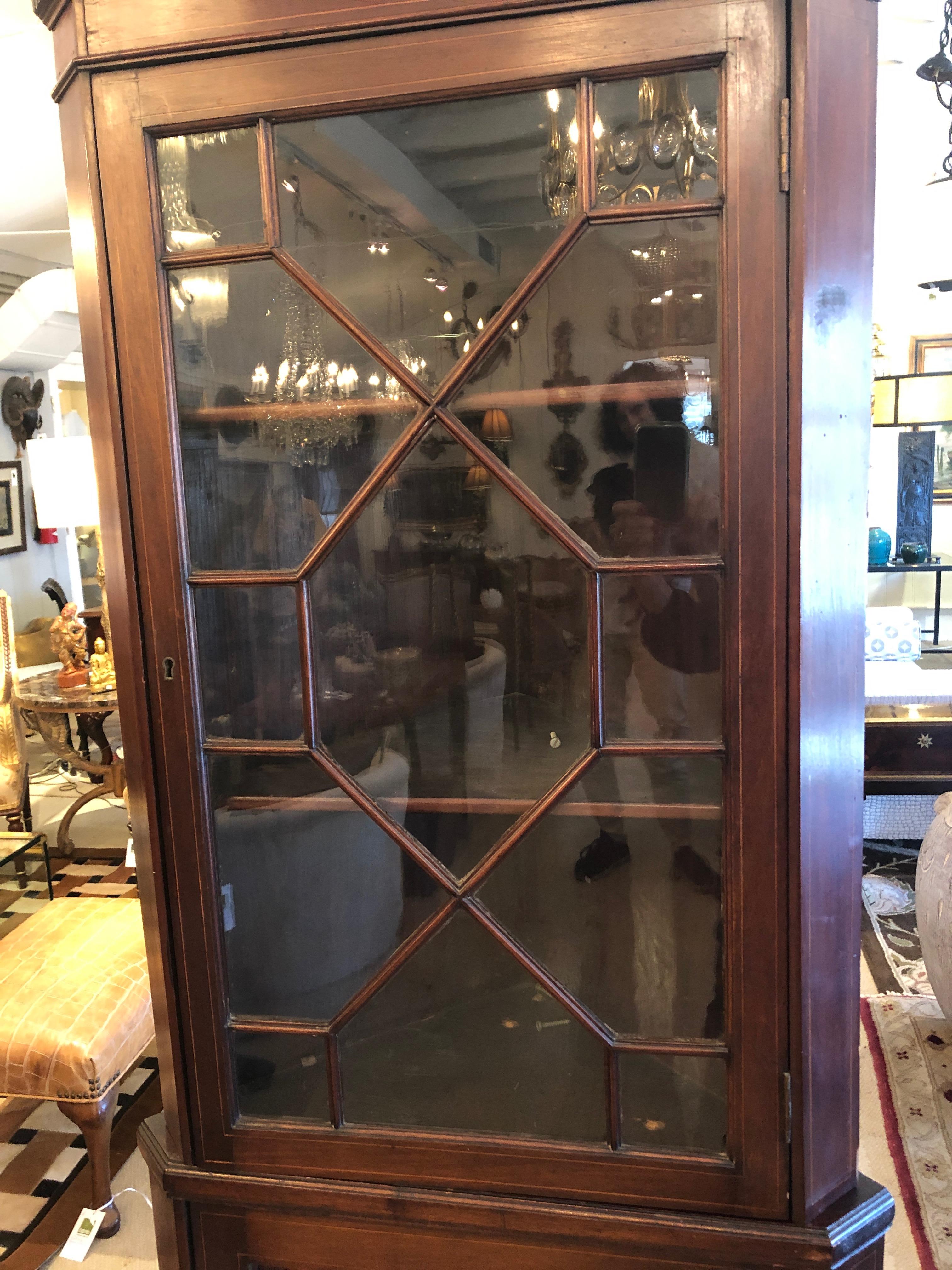 Very elegant dark mahogany Chippendale style corner cabinet having pretty satinwood inlay seashell on lower panel door and original glass in the top door. Both doors open to storage, 2 shelves on top, 1 on the bottom.
Two pieces for easy