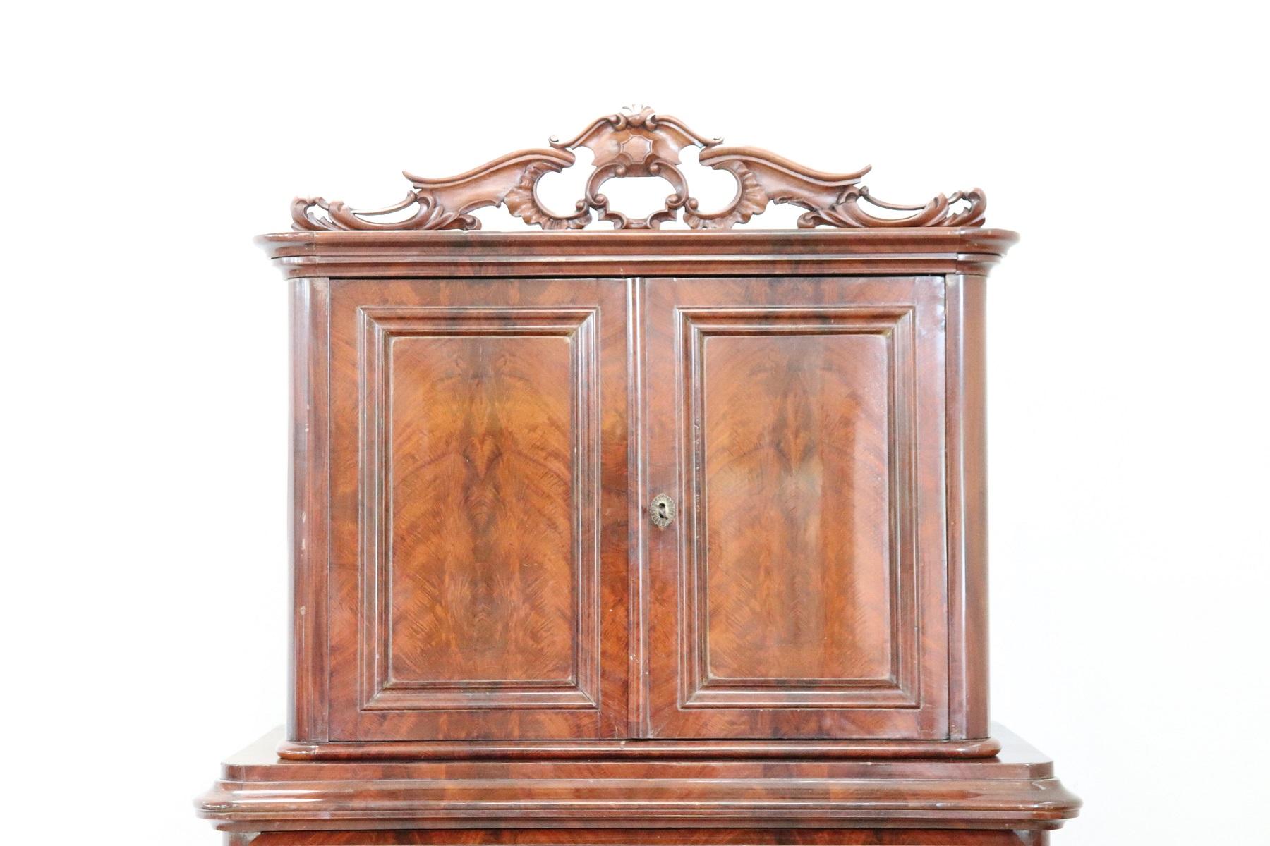 Antique English chest of drawers 1850s in mahogany wood. Very linear and essential with four comfortable drawers. On the front drawers with a particular rounded shape. Above the drawers a comfortable space with two doors. Refined decorative carving