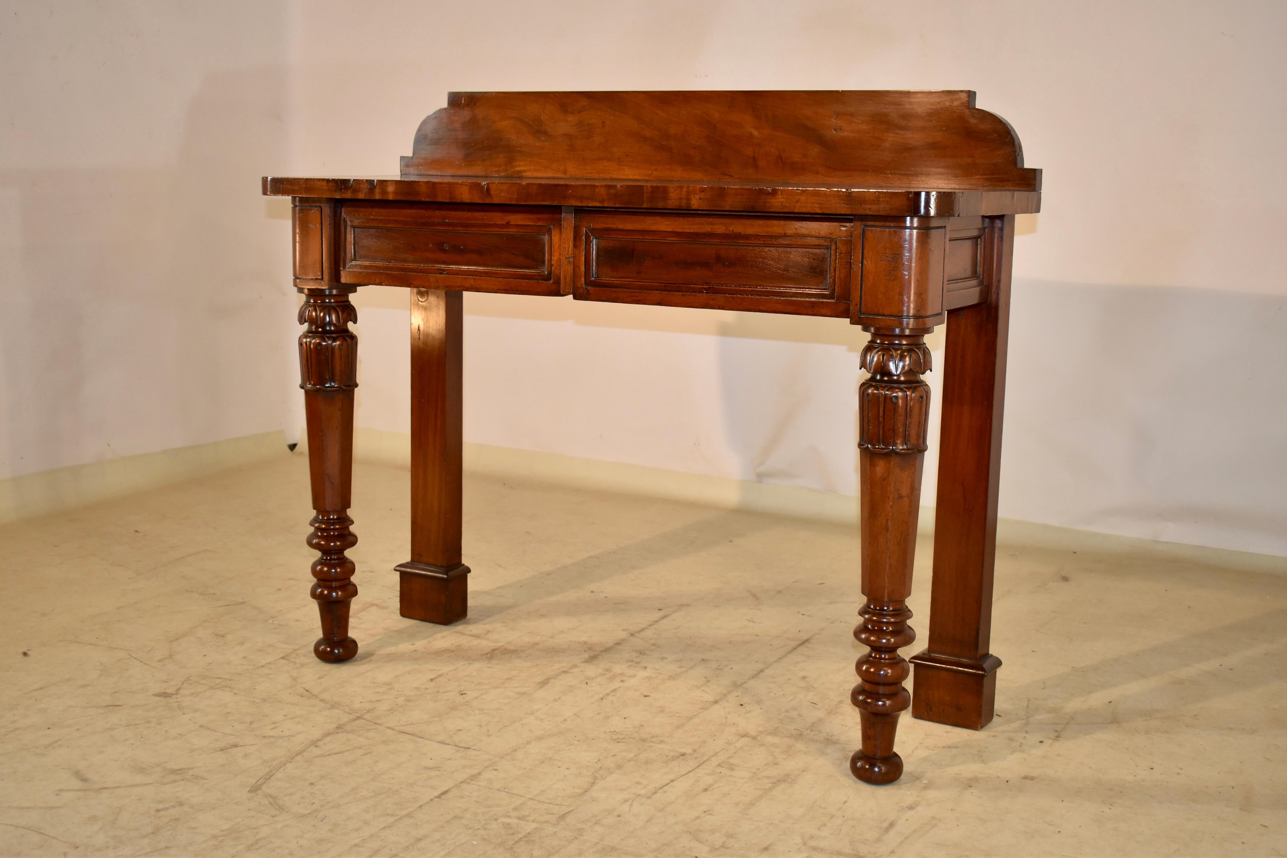 19th century mahogany console table from England with modern and clean lines.  The backsplash is nicely shaped on the ends over a gorgeously grained top.  The top follows down to simple paneled sides and two drawers in the front of the piece, which