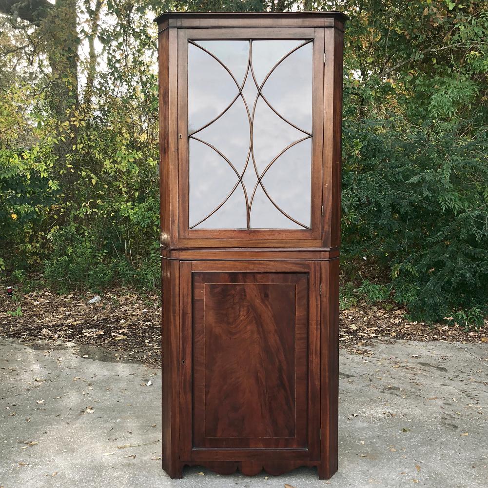 19th century English mahogany Corner Curio cabinet, vitrine is a splendid example of handcrafted elegance, with tailored architecture emphasizing the natural beauty of the exotic imported mahogany, with flame patterns appearing on the lower cabinet