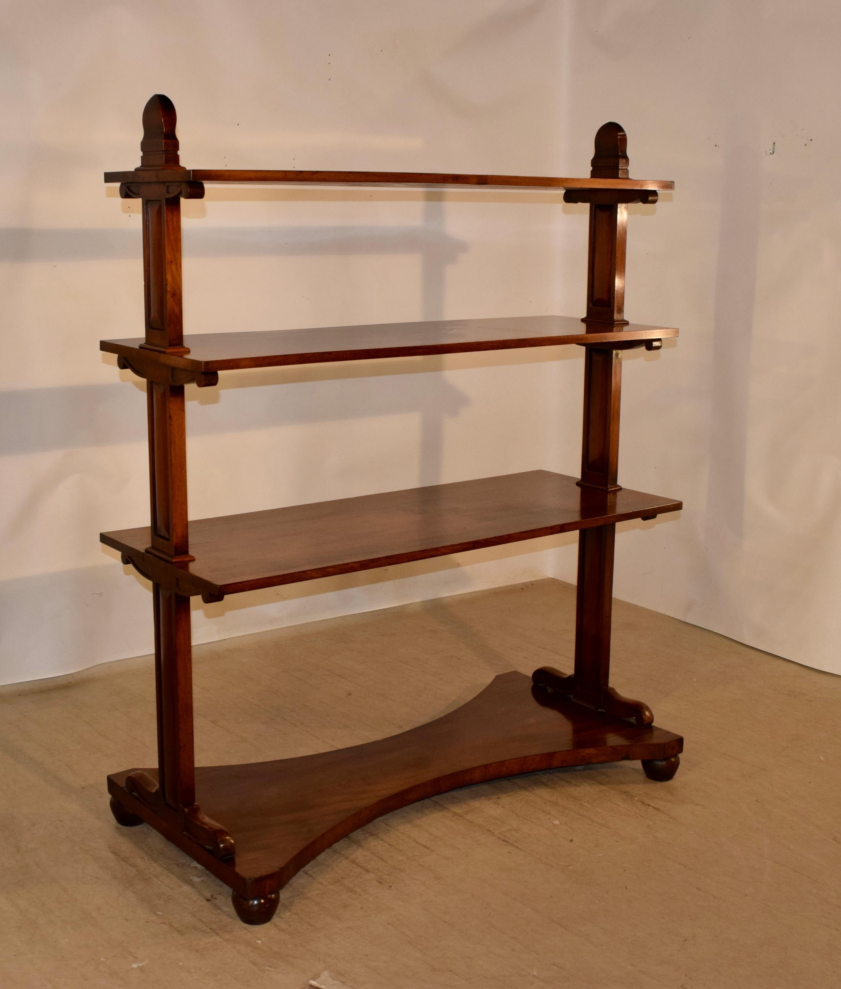 19th century English dessert buffet made from mahogany. It has three shelves, all supported by central columns with brackets. The base is shaped and is raised on hand-turned feet.