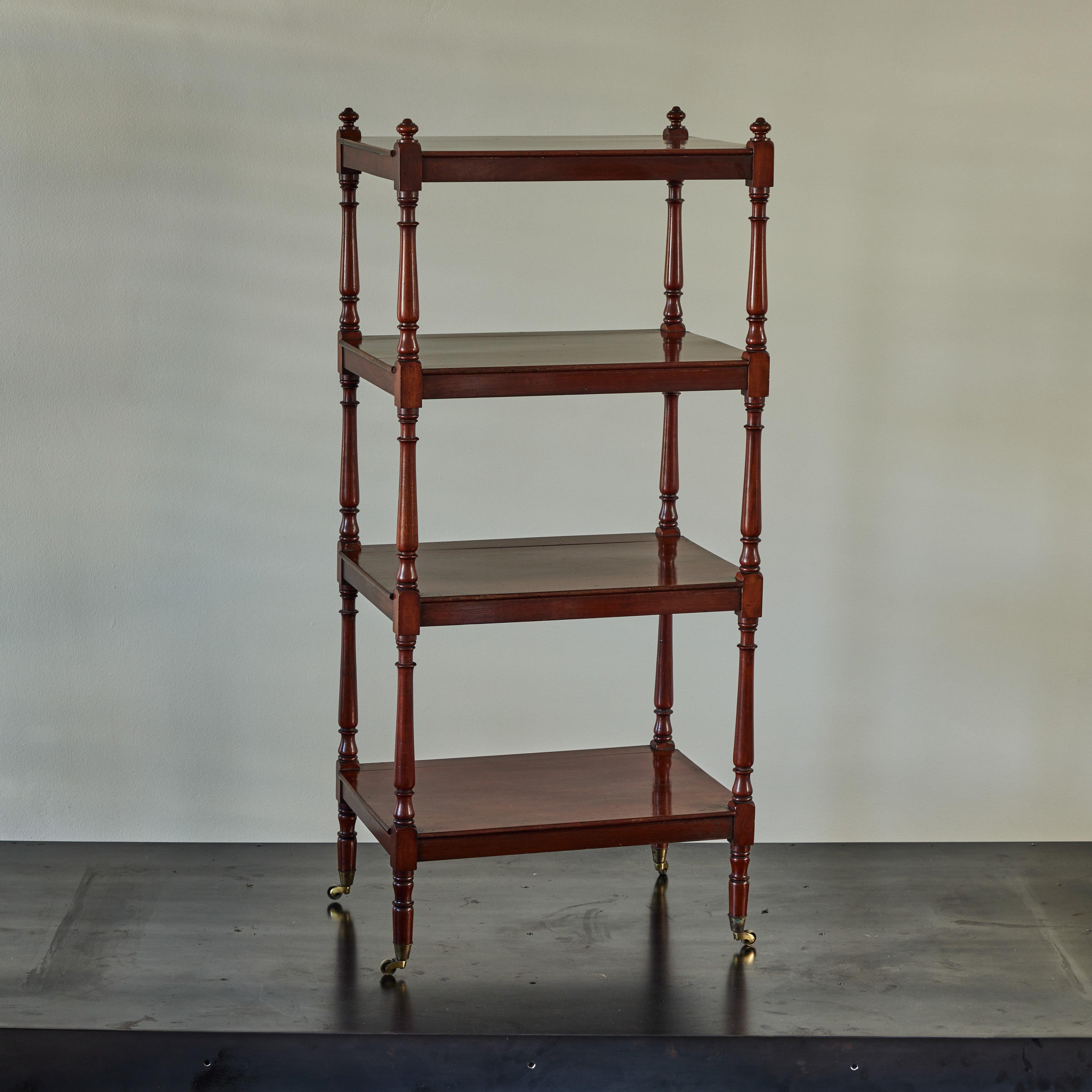 19th-Century English mahogany étagère. Featuring four well-spaced open shelves and elegant hand-carved spool shaped supports, this beautiful and traditional shelving unit is mounted on casters for increased versatility. A timeless piece with a